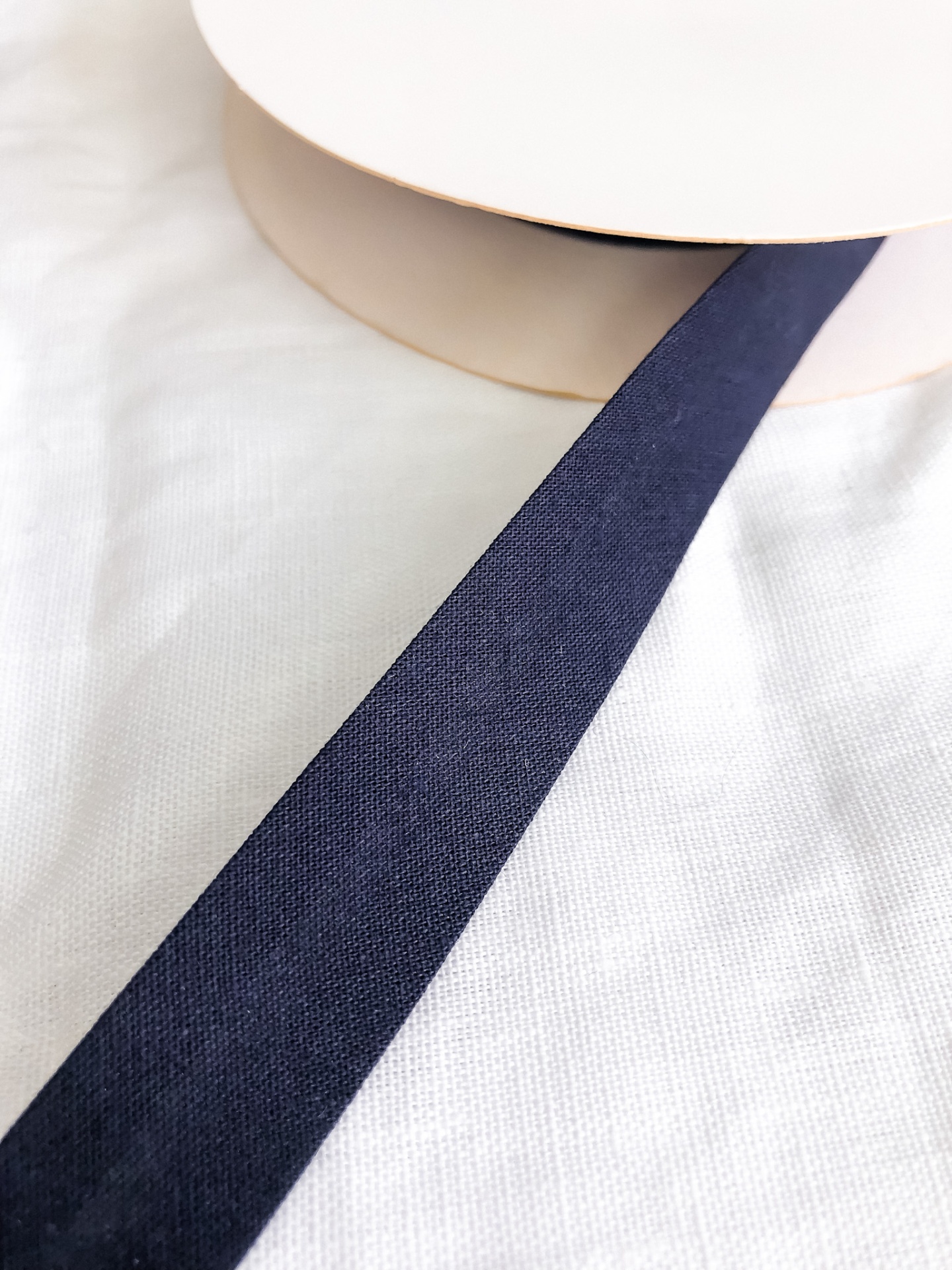 Fita azul escura enrolada em rolo bege sobre tecido branco