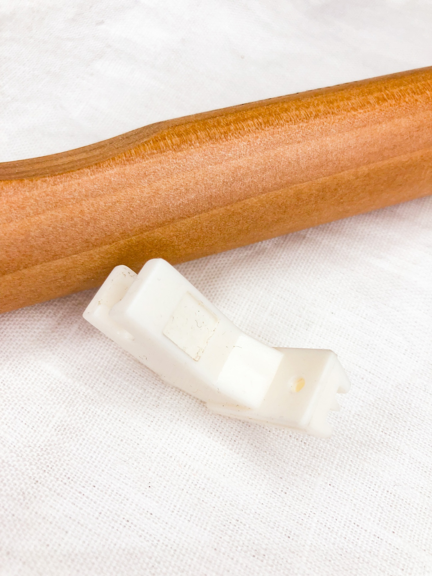 Suporte de plástico branco e objeto de madeira sobre tecido branco