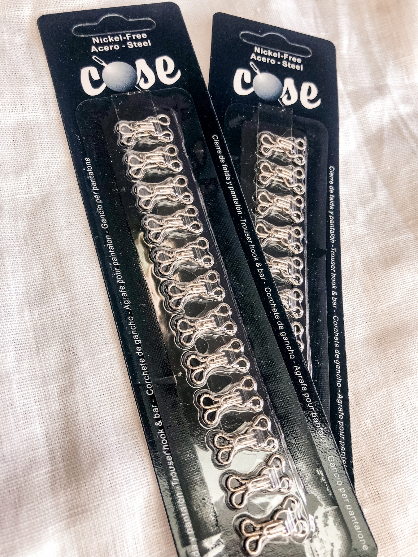 Duas embalagens de fechos metálicos prateados para roupas em cartão preto