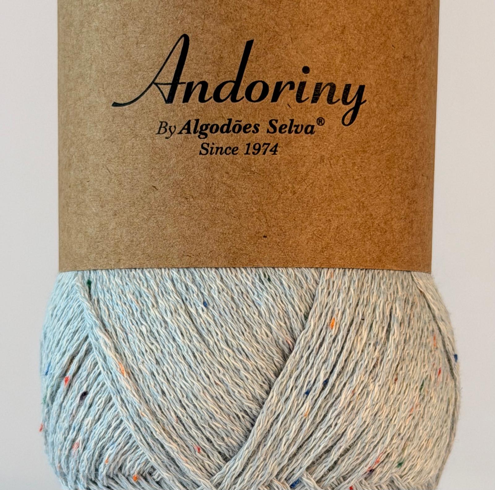 Novelo de fio de algodão cinza claro com pontos coloridos e etiqueta castanha Andoriny