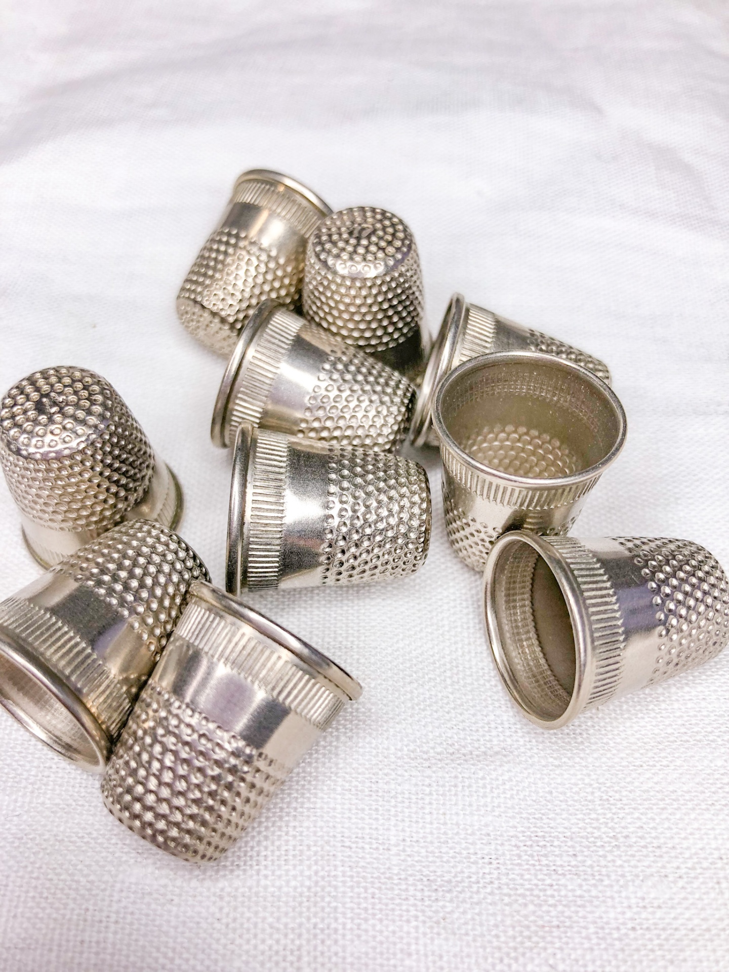 Dedais metálicos prateados texturizados sobre tecido branco.