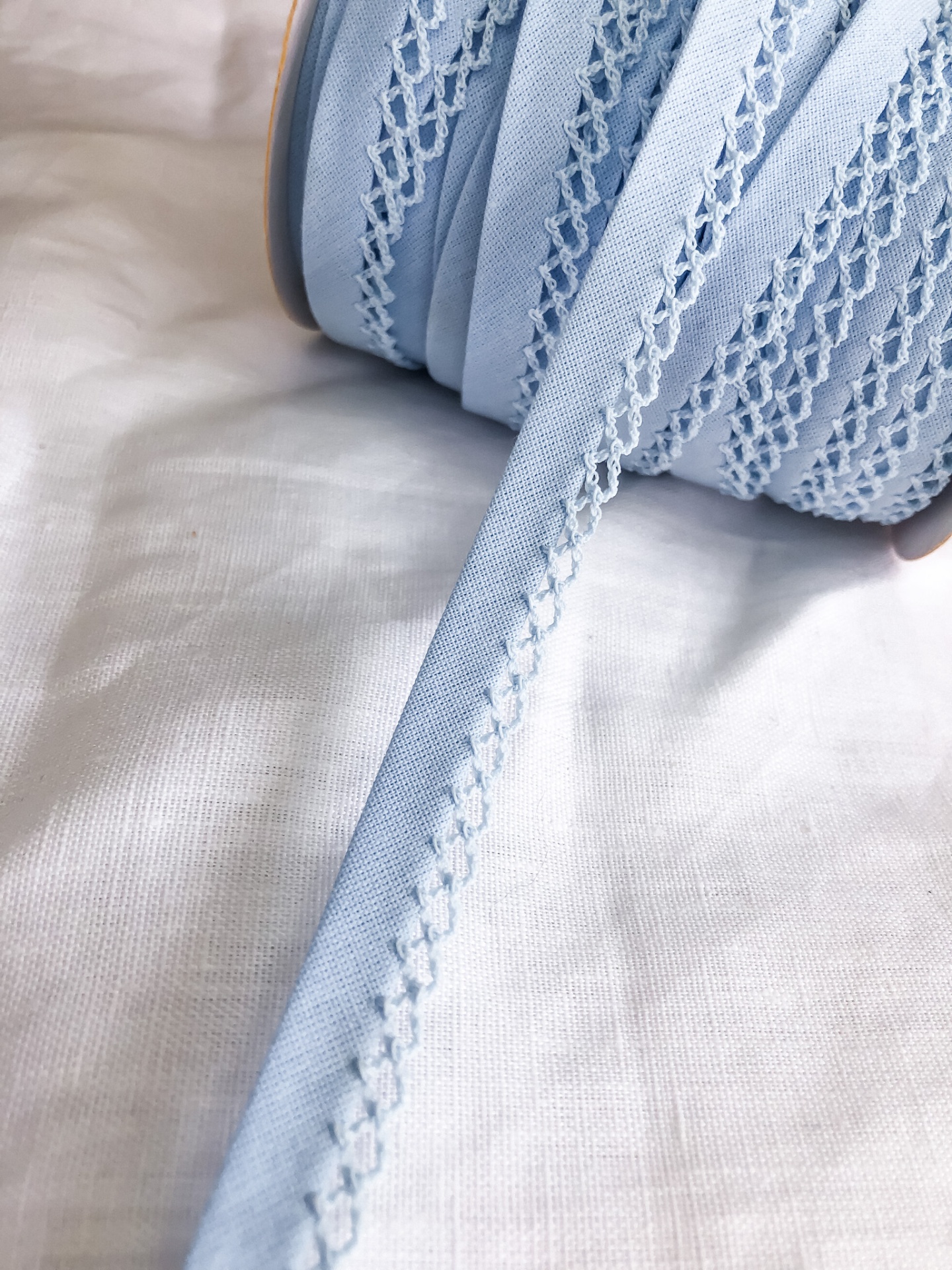 Fita têxtil azul clara com bordado branco em padrão decorativo