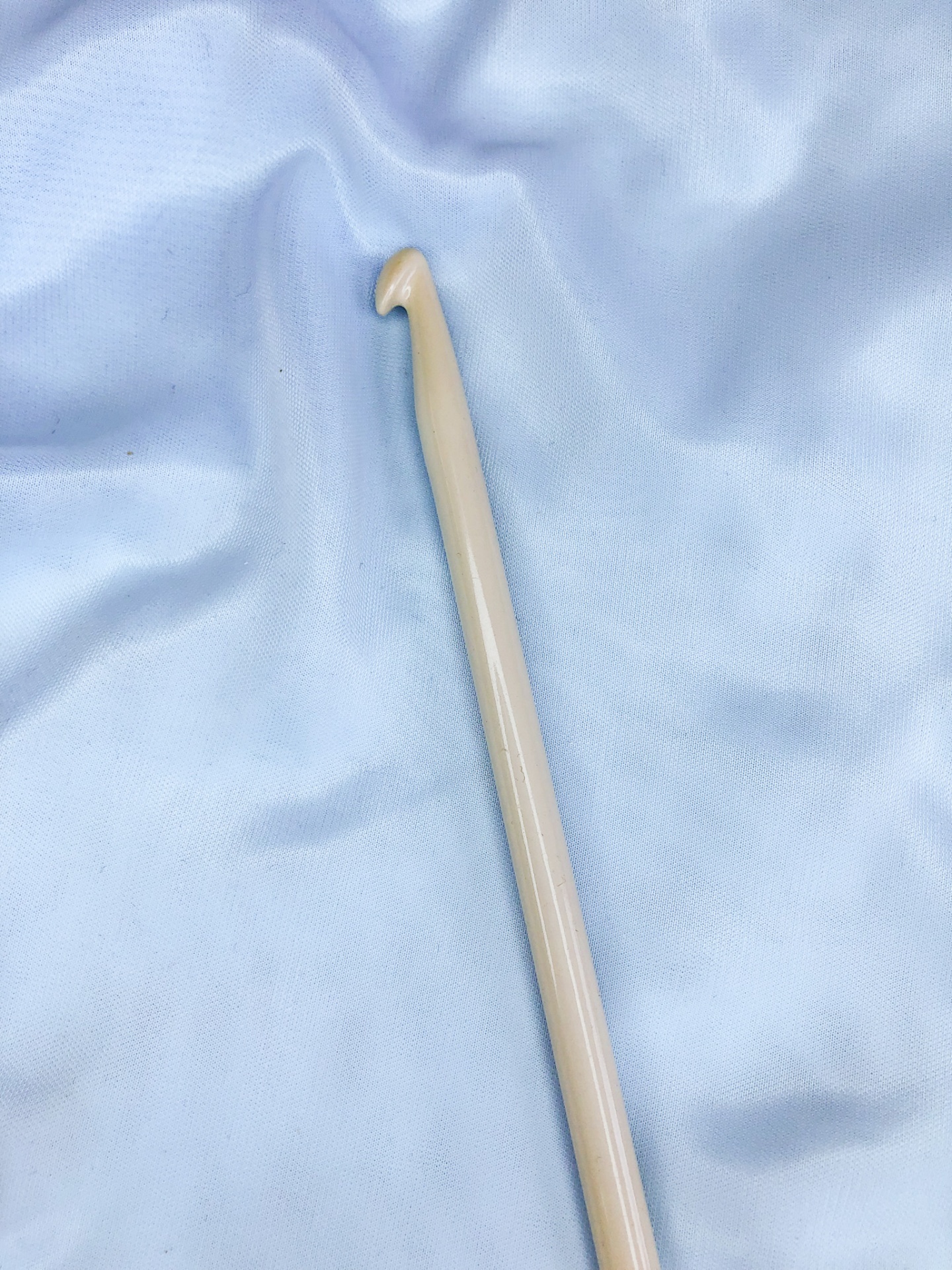 Agulha de crochet bege claro sobre tecido azul claro