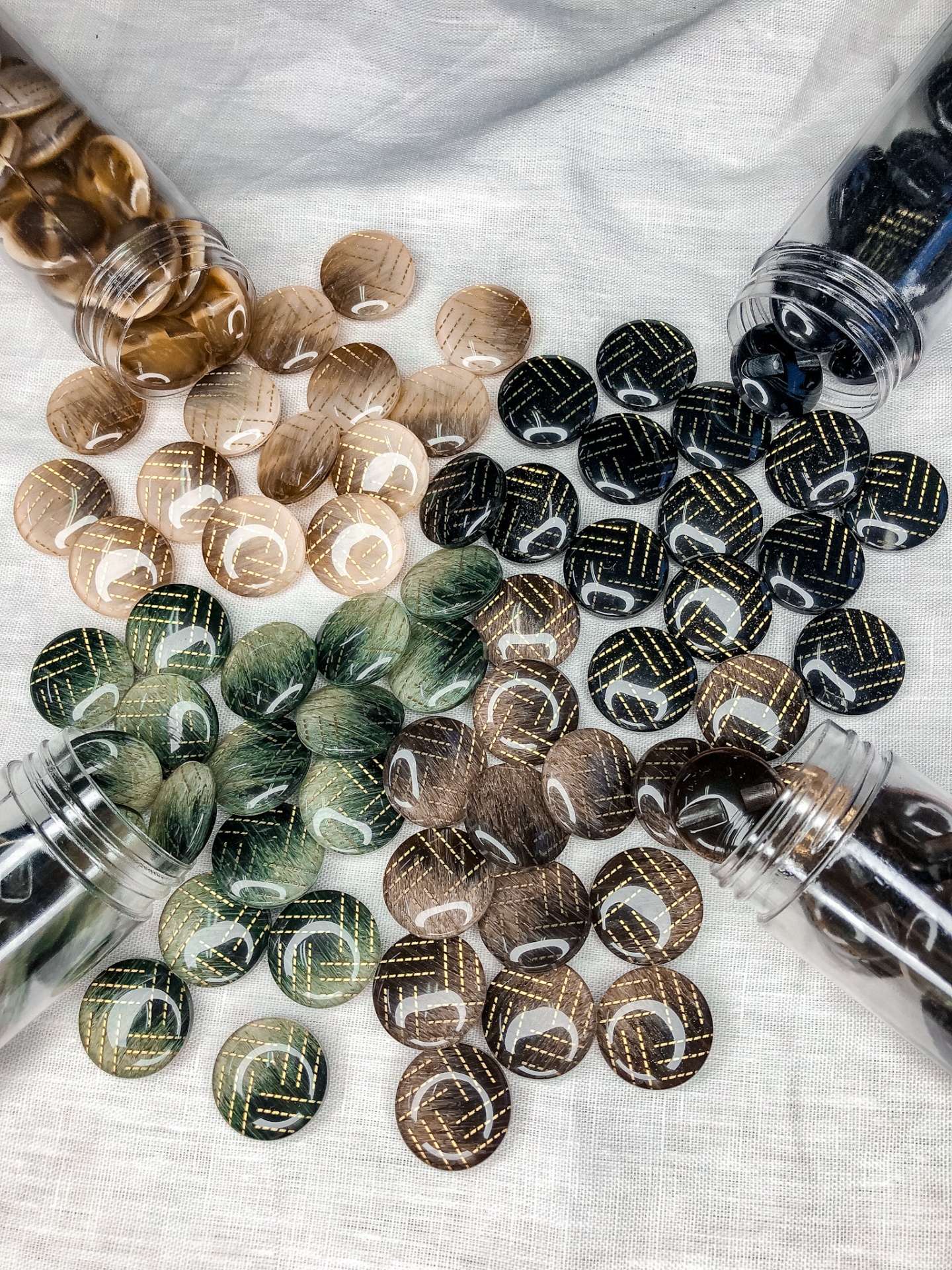 Pérolas redondas coloridas com linhas douradas em superfície branca.