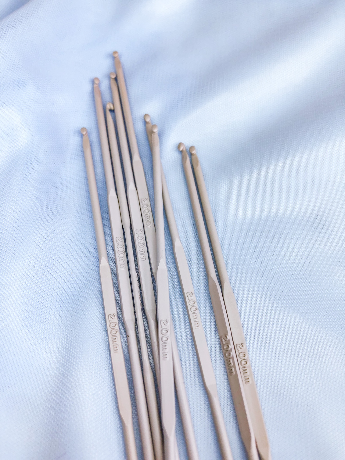 Agulhas de croché metálicas com várias espessuras sobre tecido azul claro