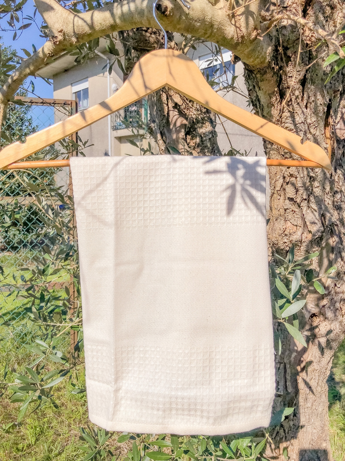 Toalha branca texturizada pendurada em cabide de madeira ao ar livre