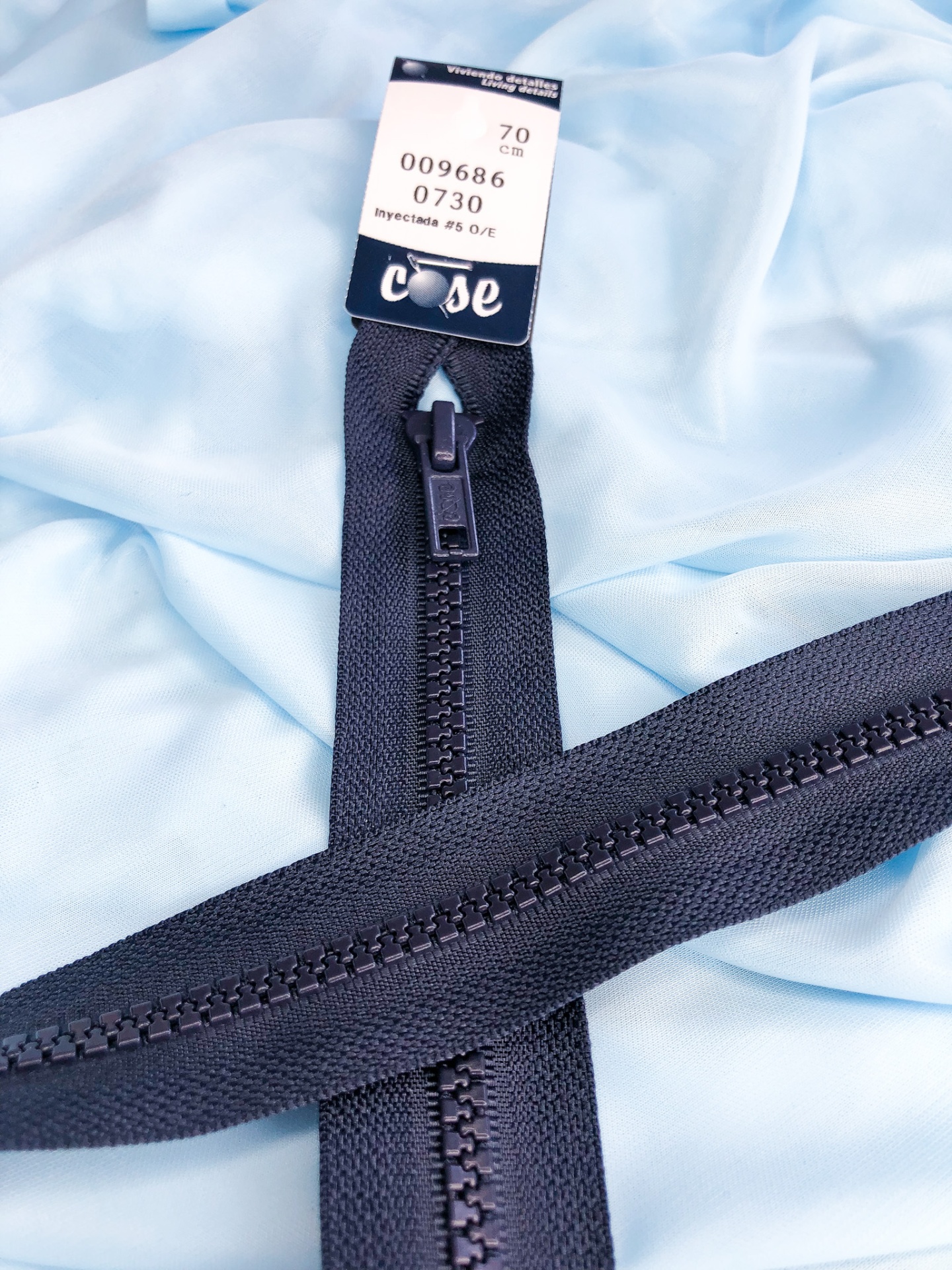 Fecho éclair preto sobre tecido azul claro com etiqueta visível