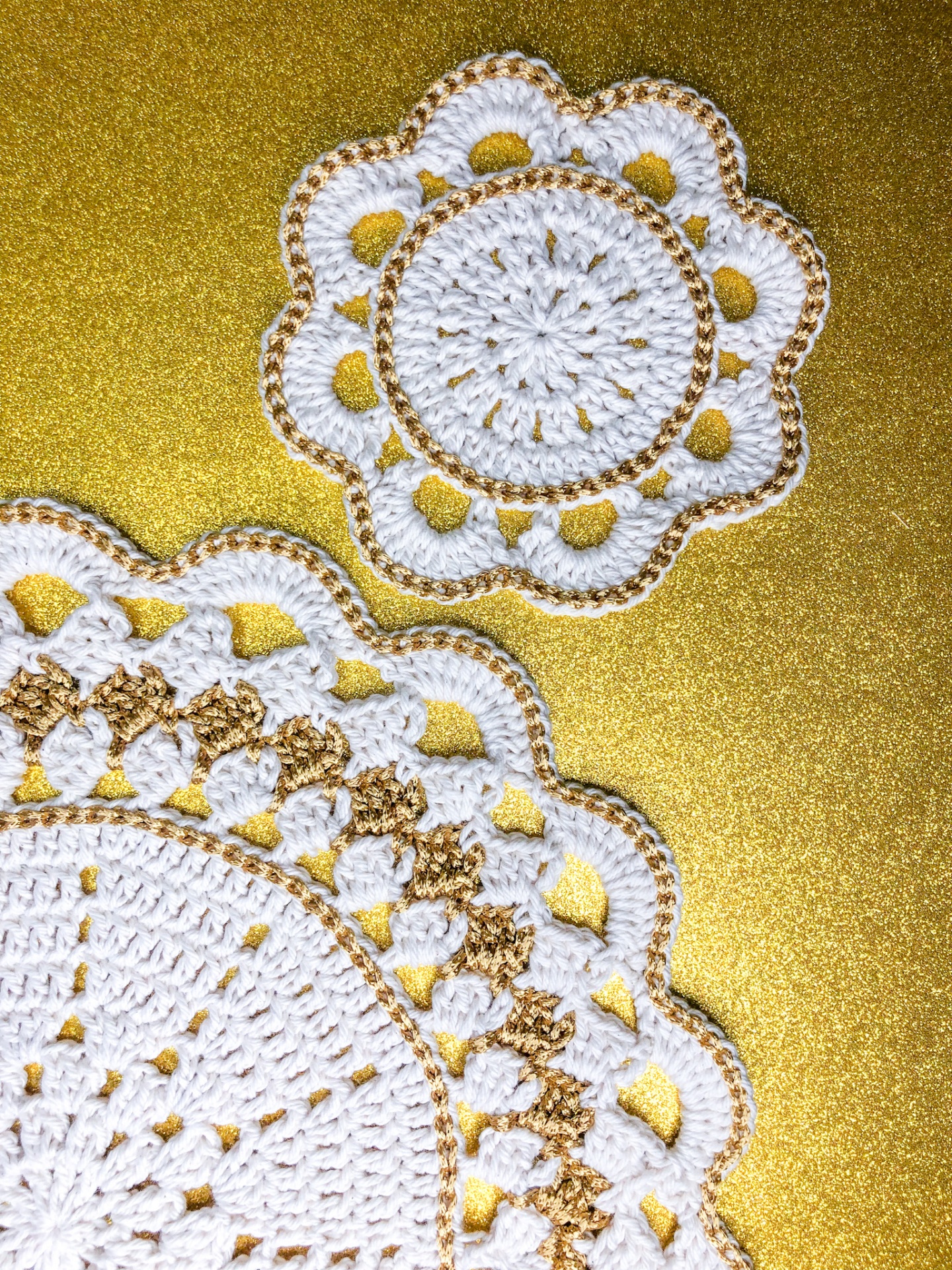 Toalhetes de croché brancos com detalhes dourados sobre superfície dourada brilhante