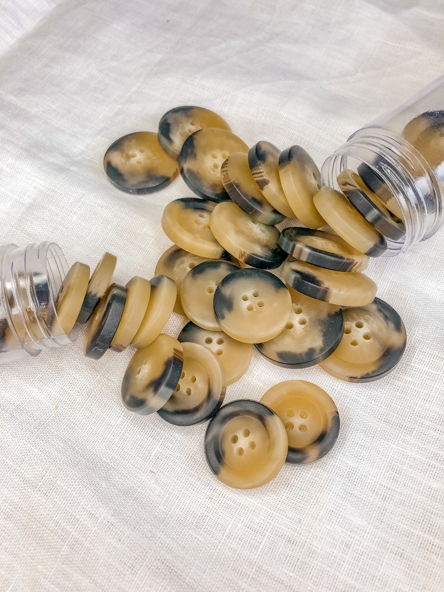 Botões redondos bege com manchas pretas em tecido branco e tubos plásticos.