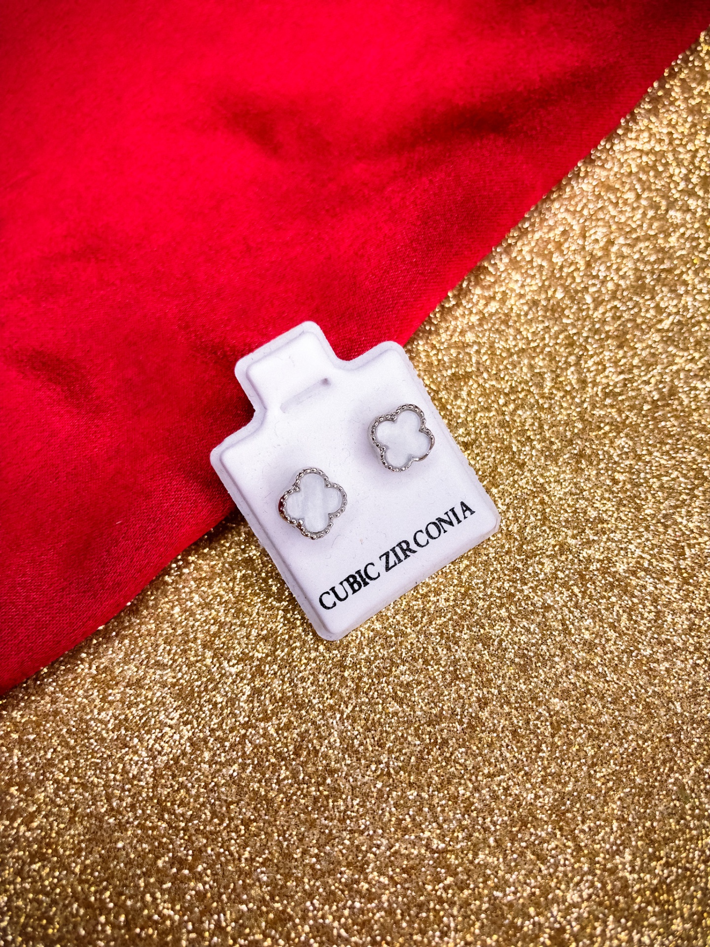 Brincos em forma de flor branca com moldura prateada em cartão branco