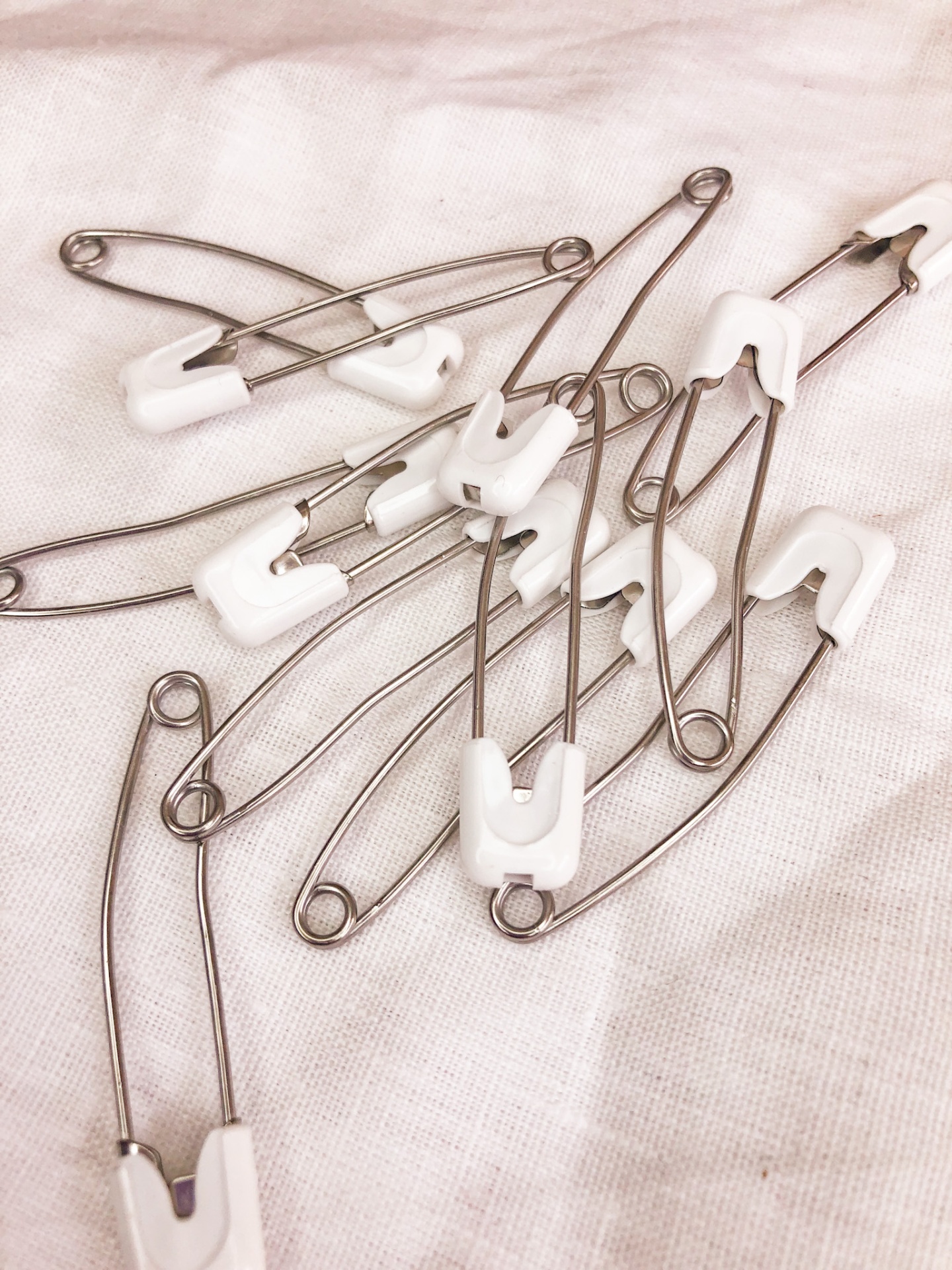 Alfinetes de segurança metálicos com proteção branca sobre tecido branco