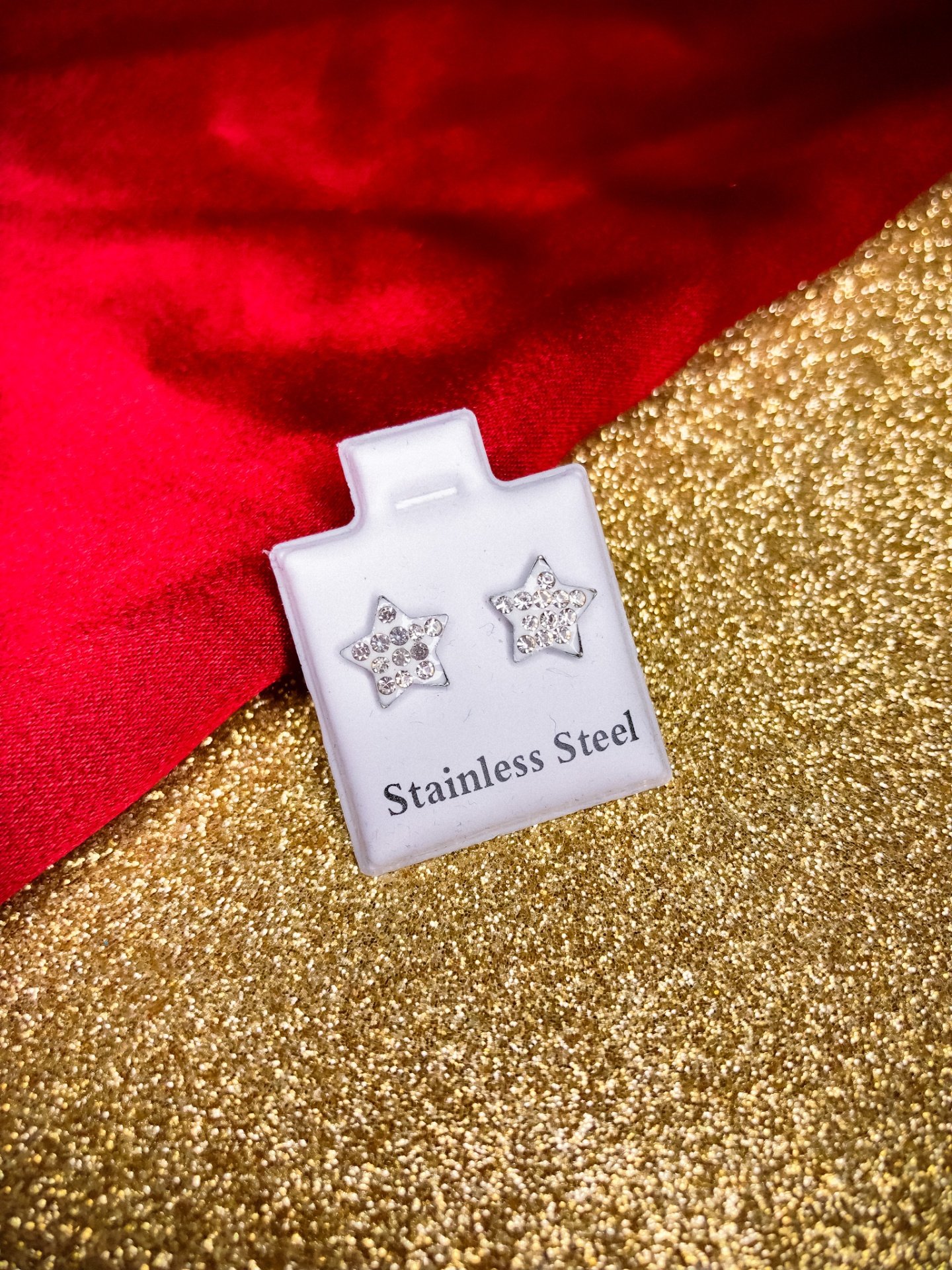 Brincos estrelas de aço inoxidável com cristais num suporte branco