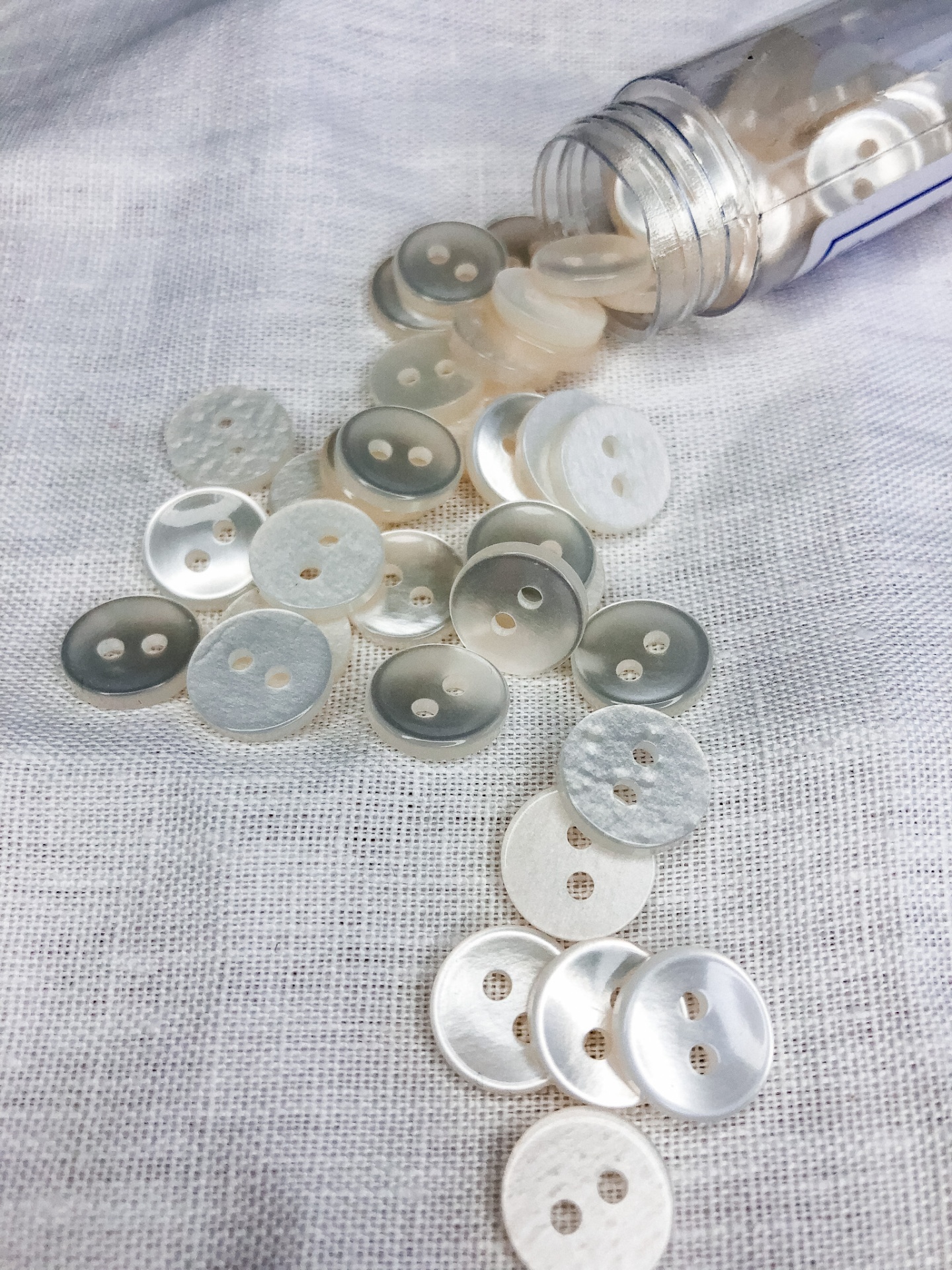 Botões redondos brancos e cinza claro sobre tecido branco