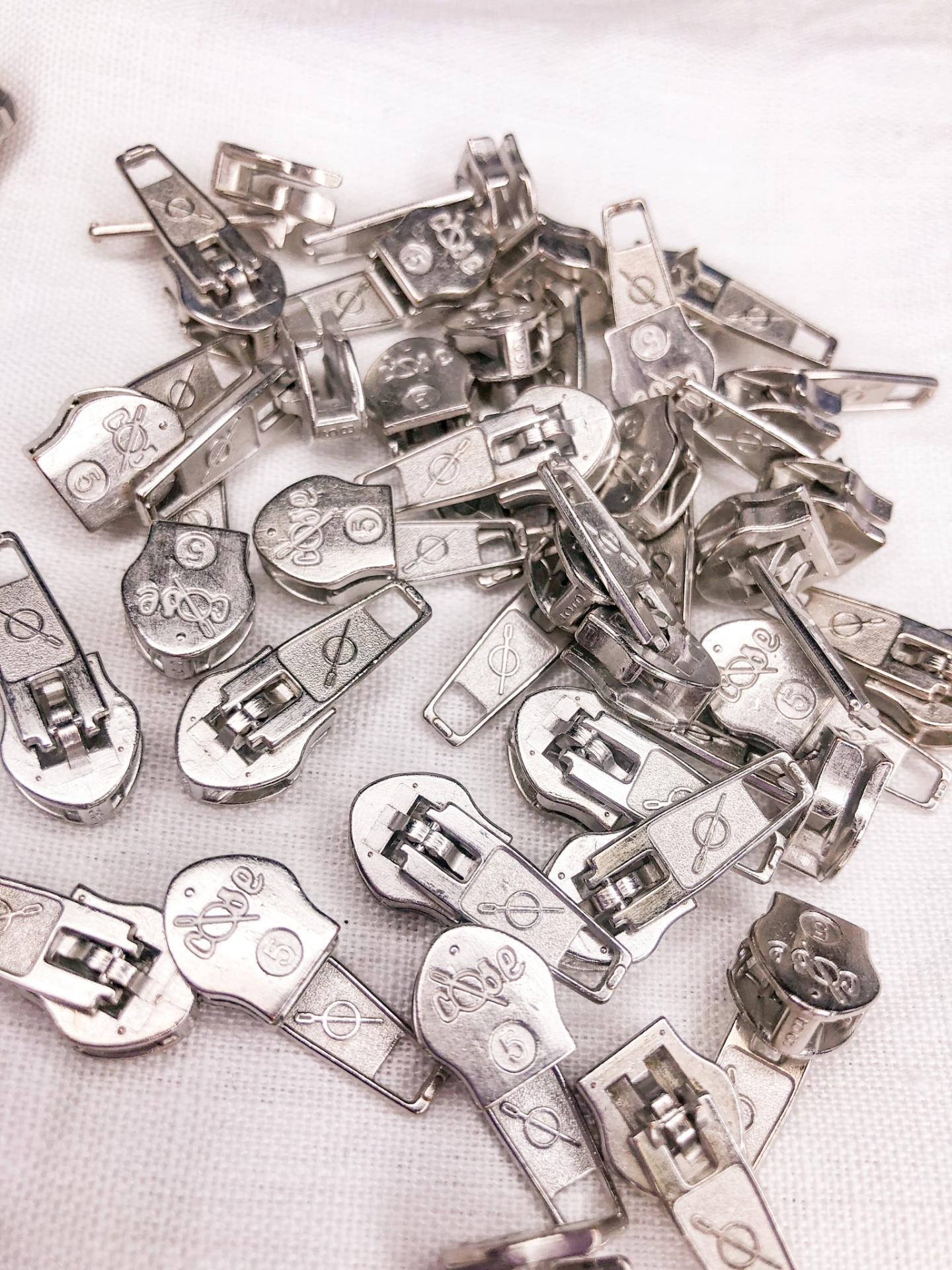 Puxadores metálicos prateados para fechos éclair com inscrições e símbolos