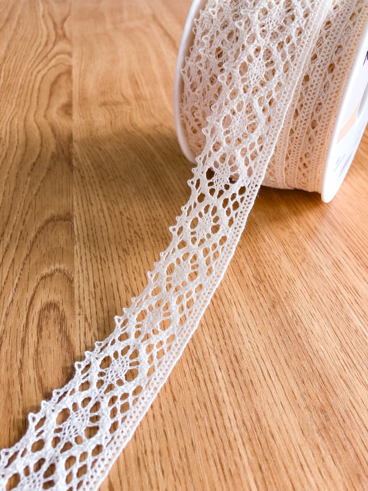Renda branca decorativa com padrão floral sobre madeira clara
