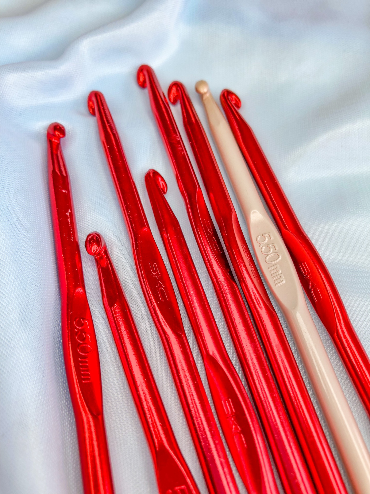 Agulhas de croché vermelhas e bege em tecido branco