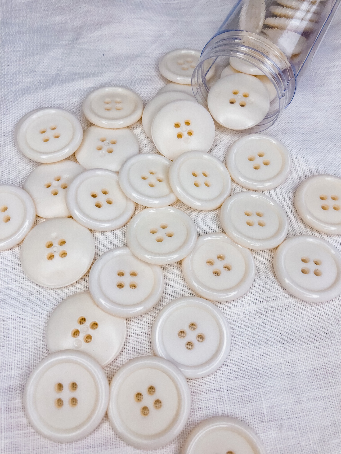 botões brancos com 4 furos em tecido branco e tubo plástico