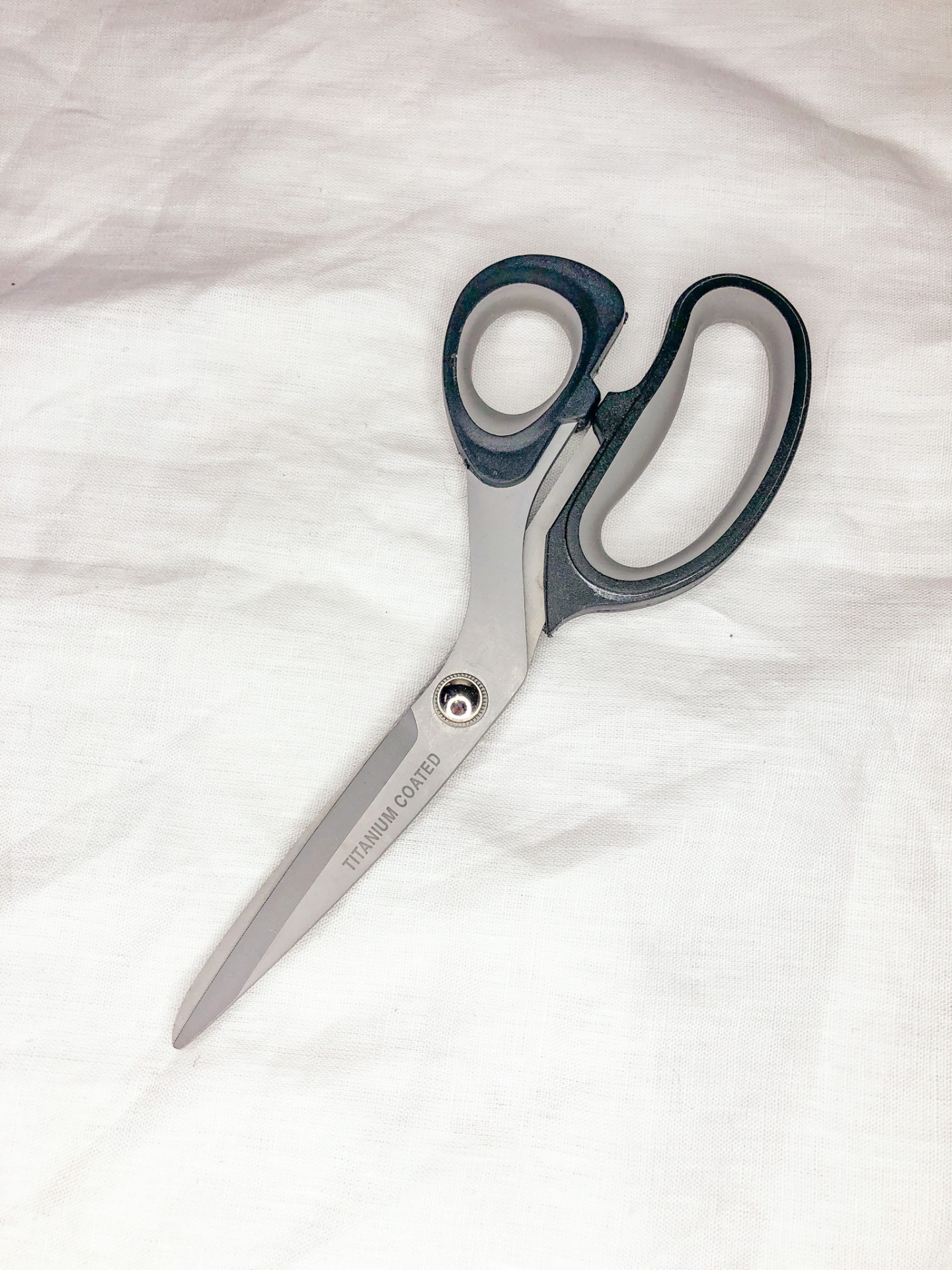 Tesoura de lâminas metálicas prateadas e cabo preto sobre fundo branco