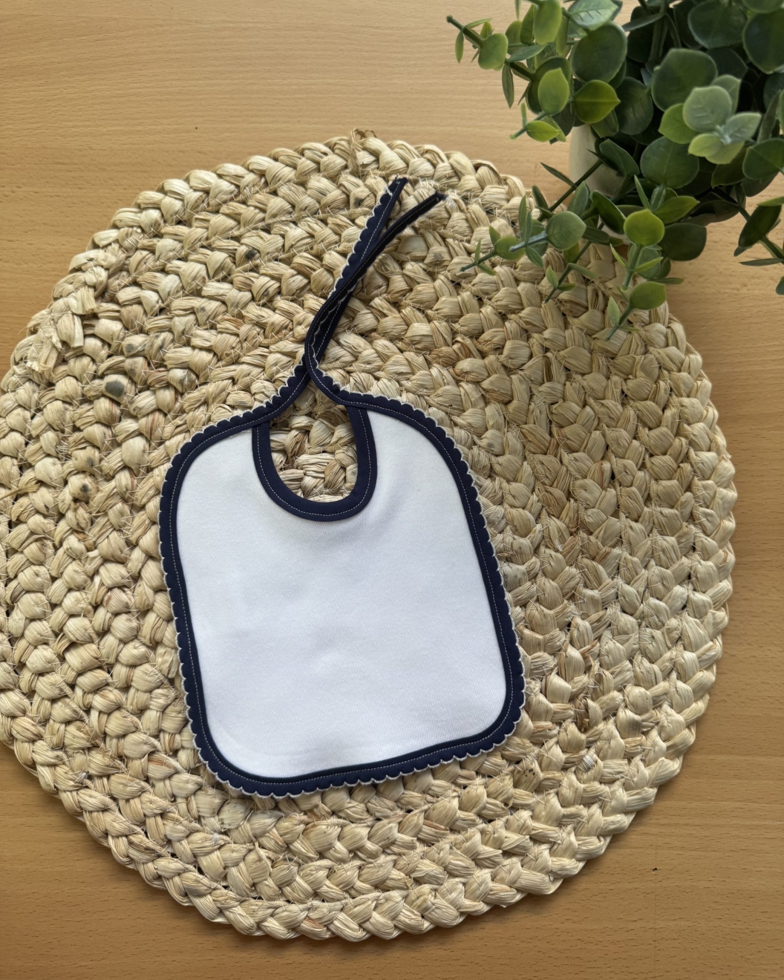 Babete branco com borda azul escura em suporte trançado natural
