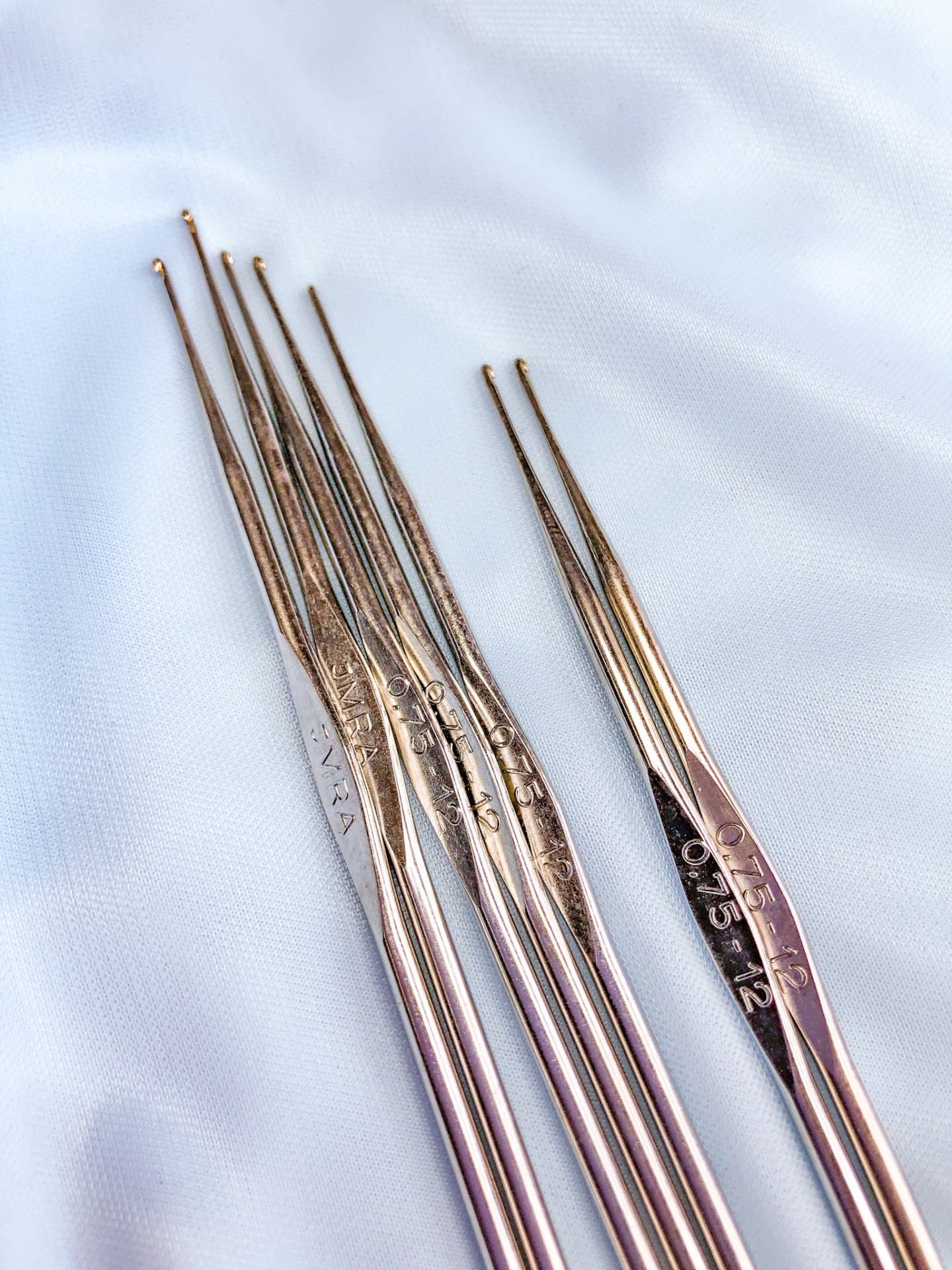 Agulhas de crochet metálicas numeradas sobre tecido branco