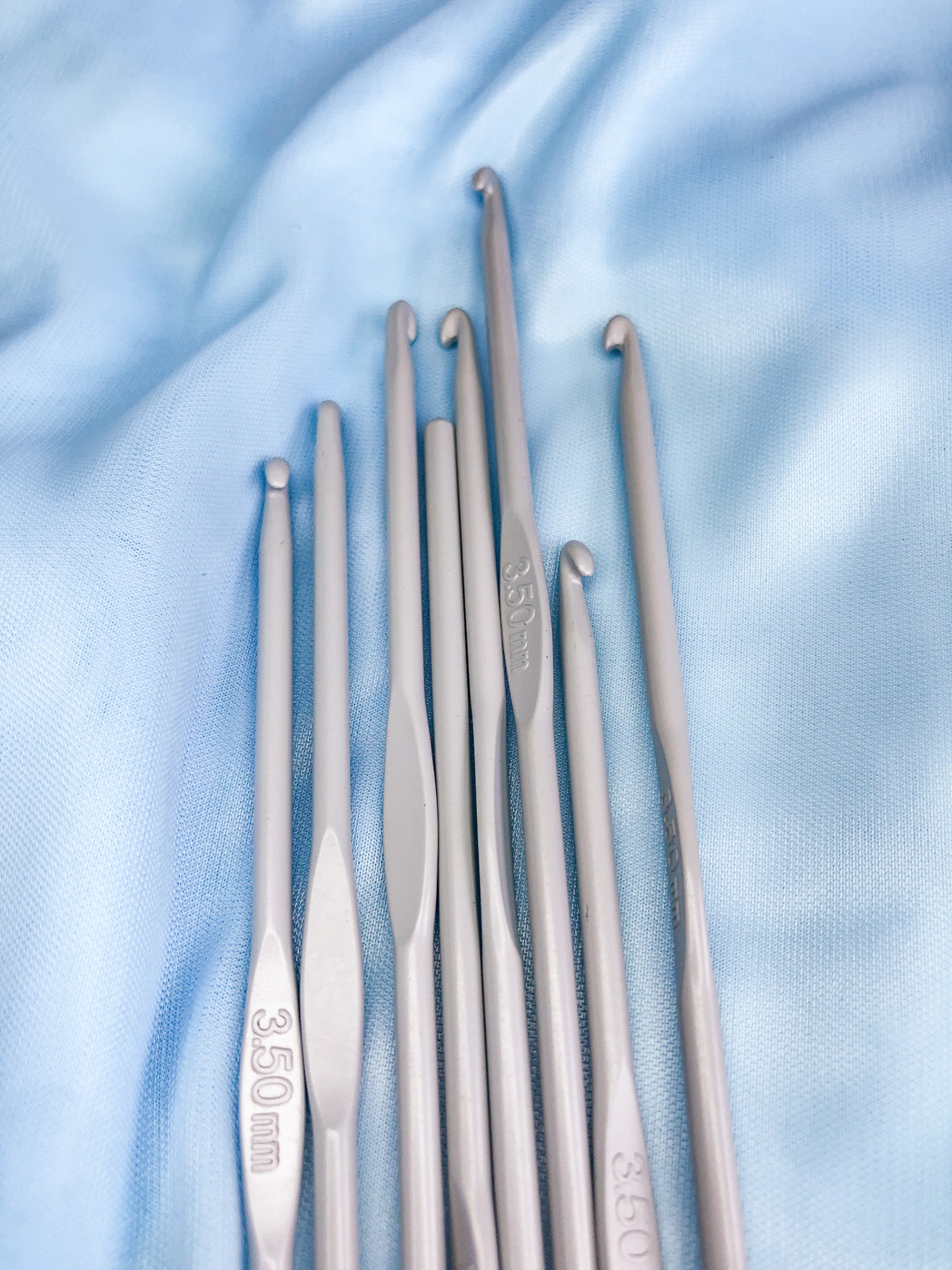 Conjunto de agulhas de crochet cinzentas sobre tecido azul claro