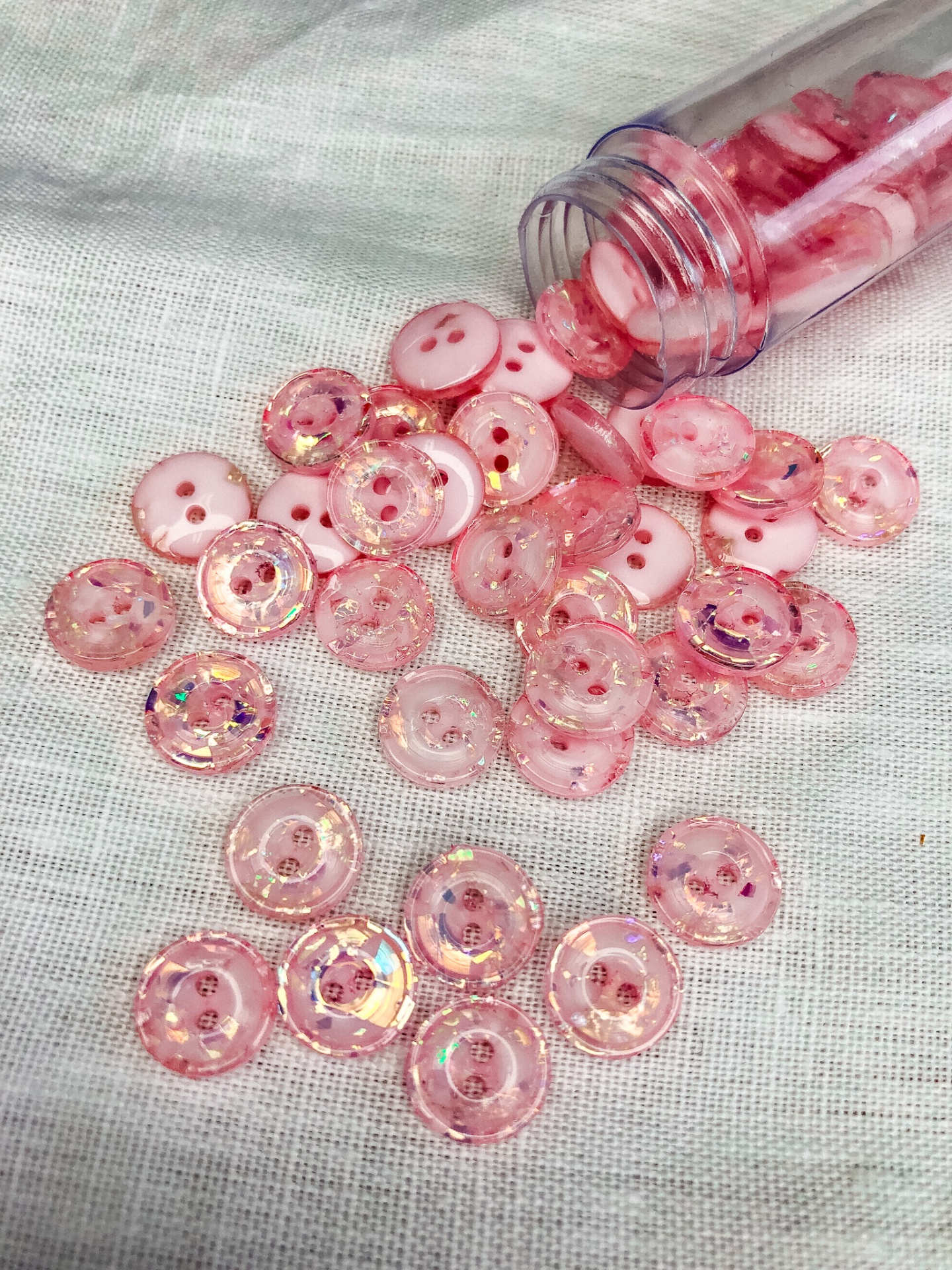 Botões rosa sólidos e transparentes brilhantes espalhados numa superfície branca
