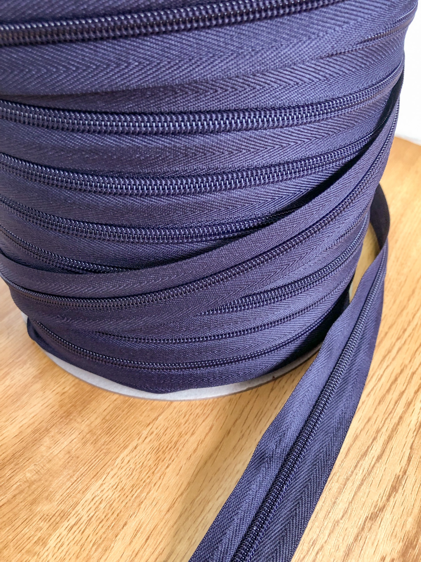 Rolo de fecho éclair cinzento escuro em superfície de madeira