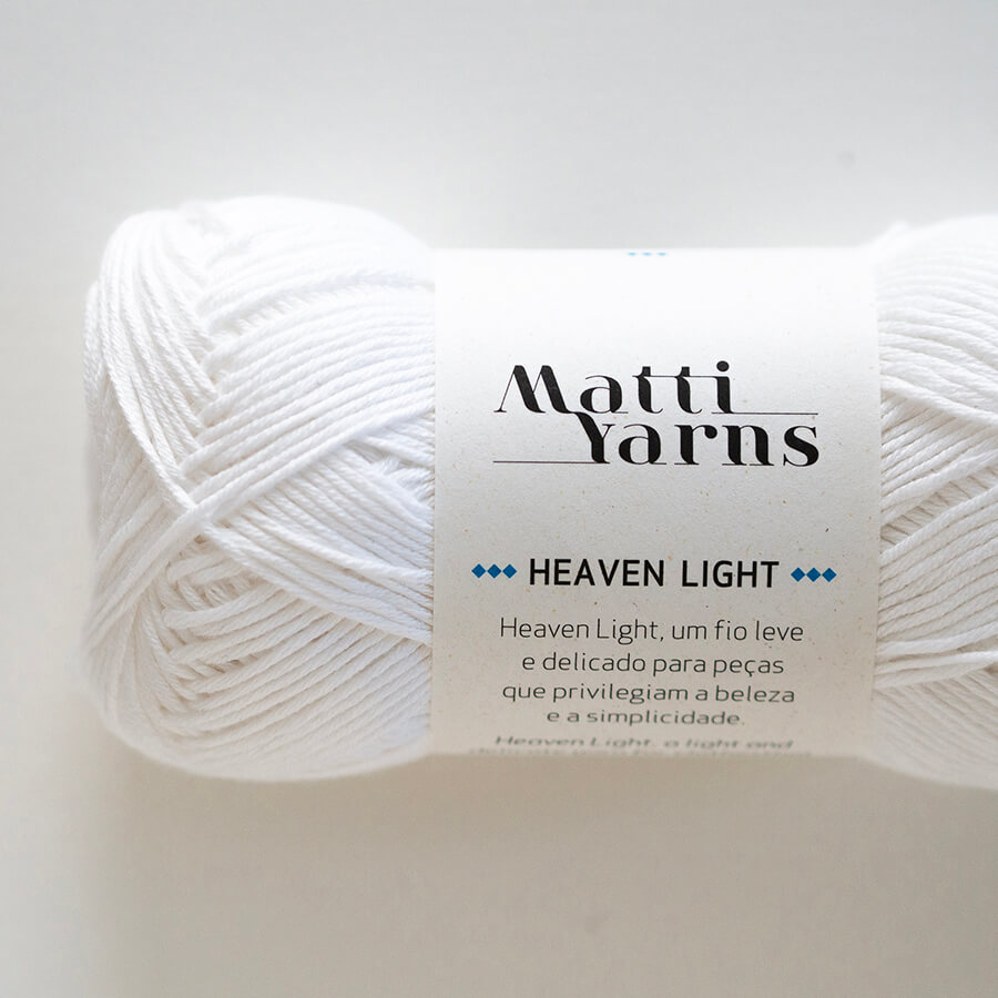 Novelo de fio branco com rótulo 'Matti Yarns Heaven Light'