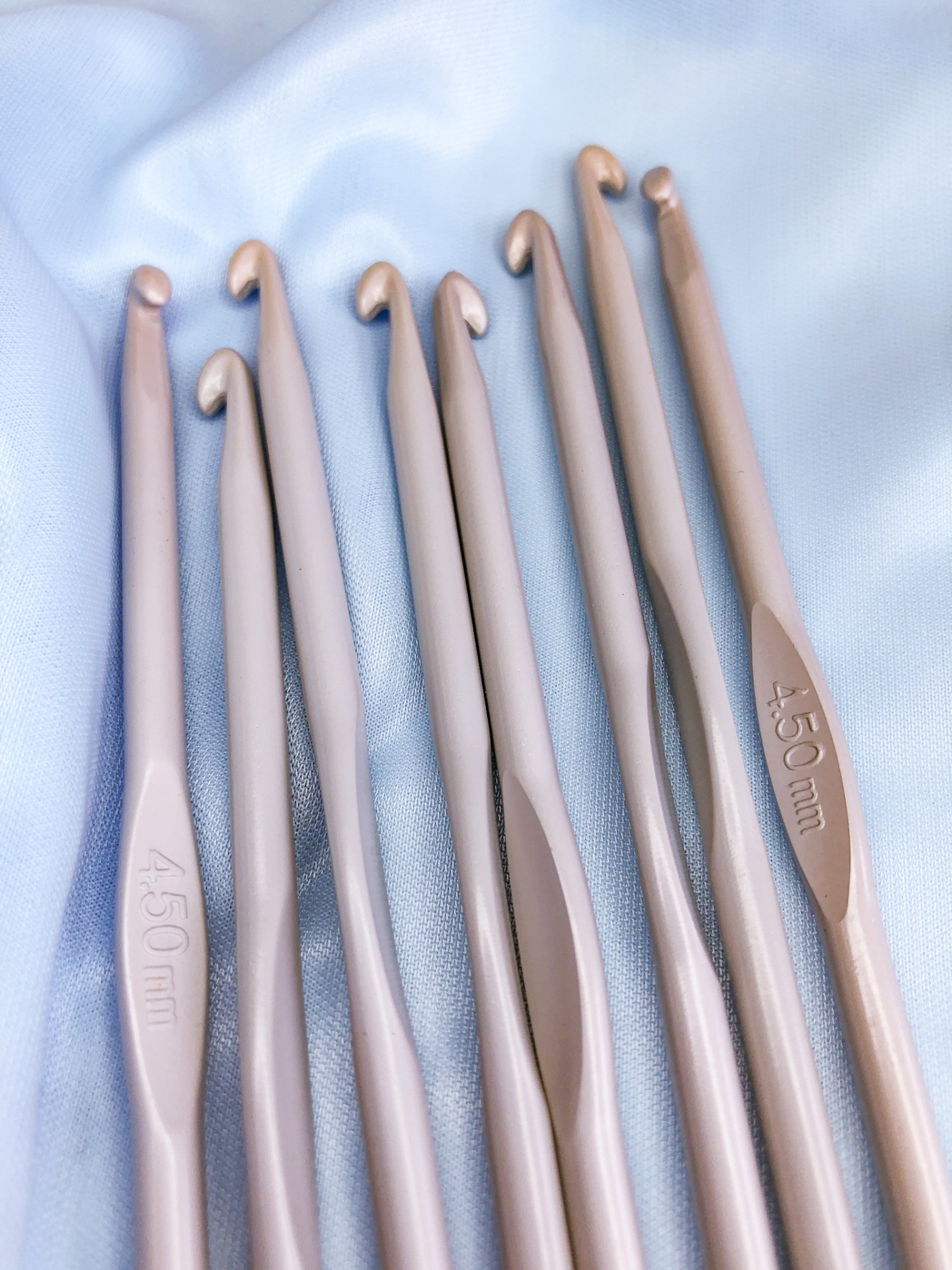 Conjunto de agulhas de crochê rosa claro sobre tecido branco