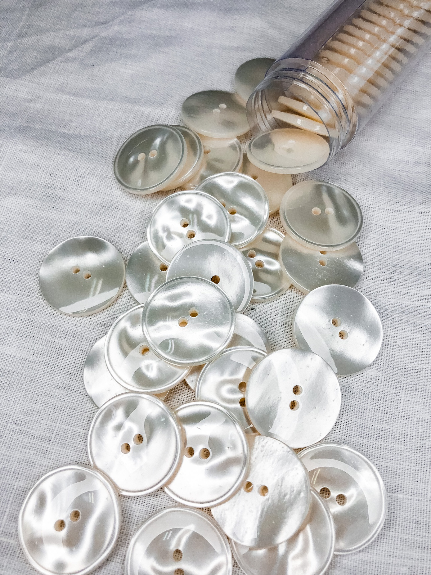 Botões de madrepérola redondos e perolados sobre tecido branco