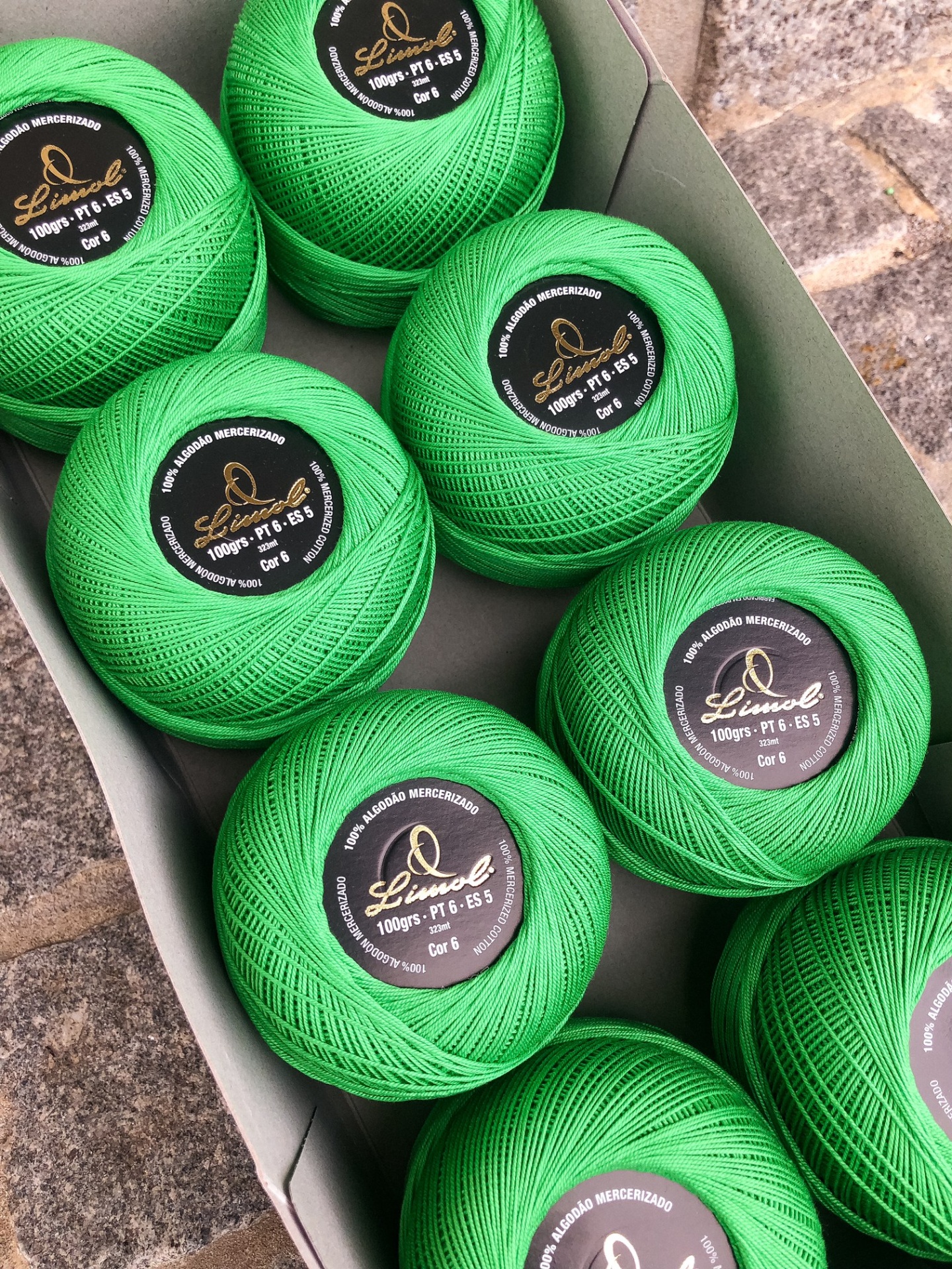 Pacote com nove novelos de linha verde com etiquetas pretas e douradas