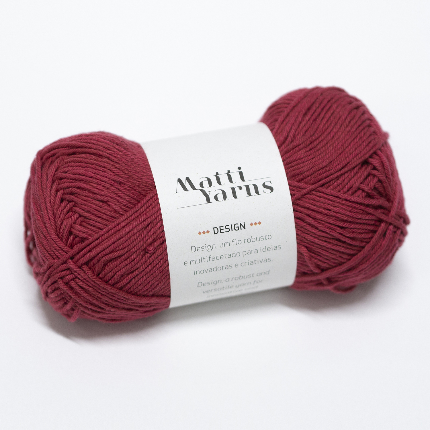 Novelo de lã vermelho escuro com etiqueta etiquetada 'Matti Yarns DESIGN'