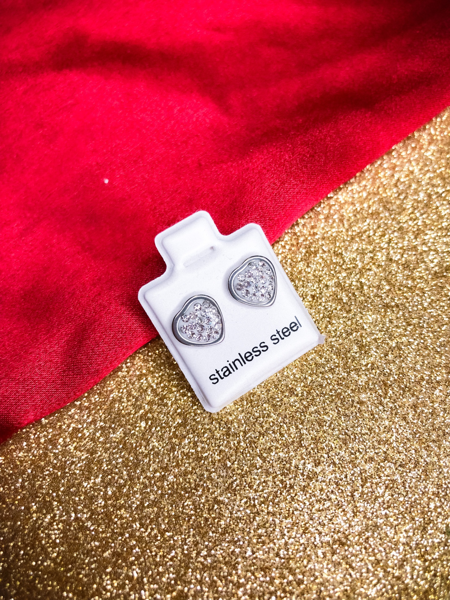 Brincos de aço inoxidável em forma de coração com brilhantes sobre suporte branco