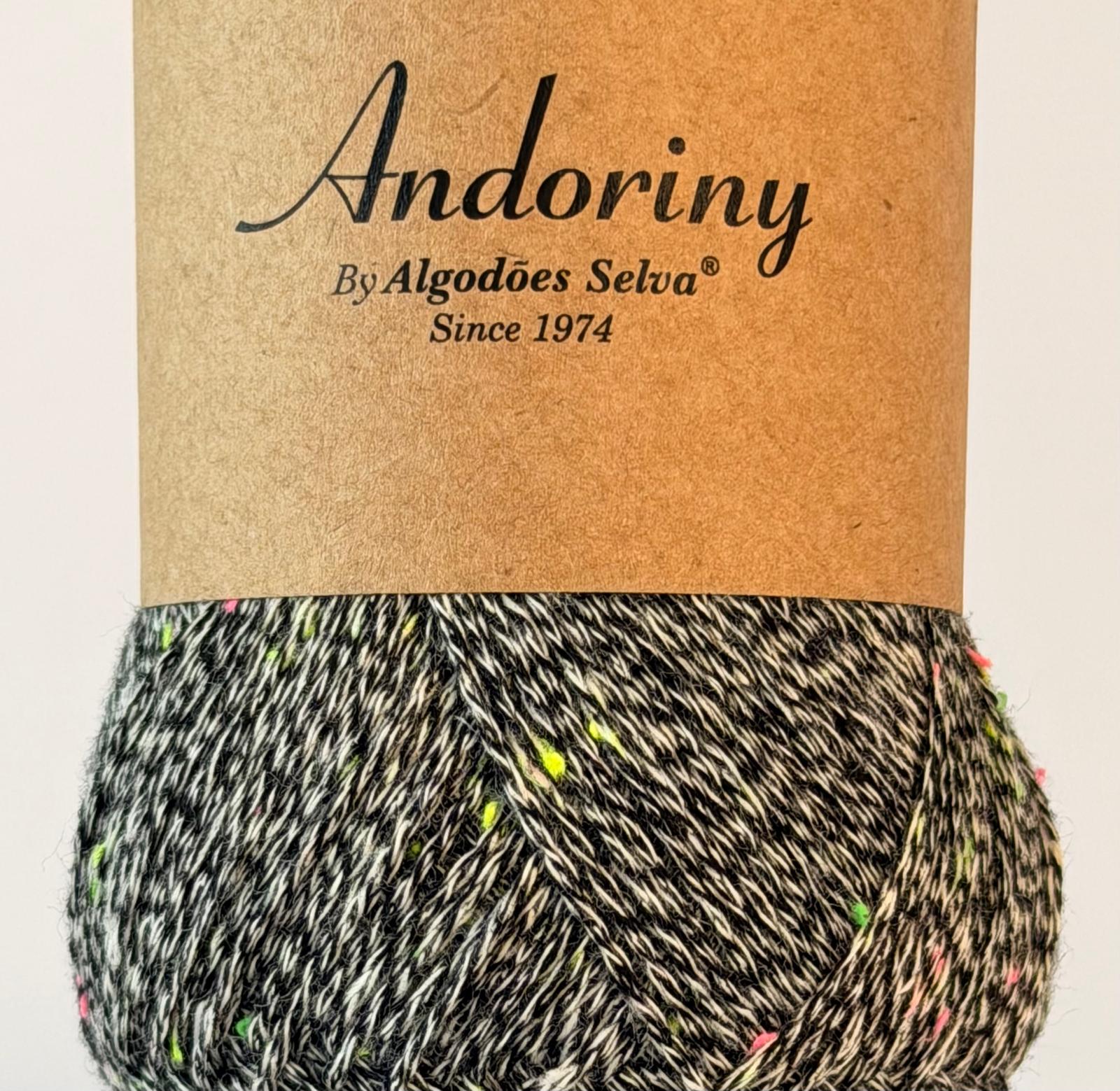 Rolo de fio multicolorido com etiqueta de papel castanho e texto Andoriny By Algodões Selva Since 1974