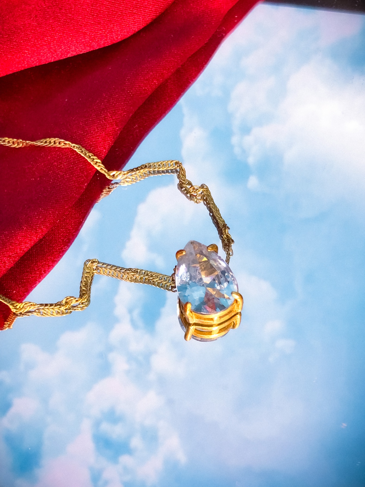 Colar com pendente de pedra azul sobre fundo refletindo céu azul e nuvens