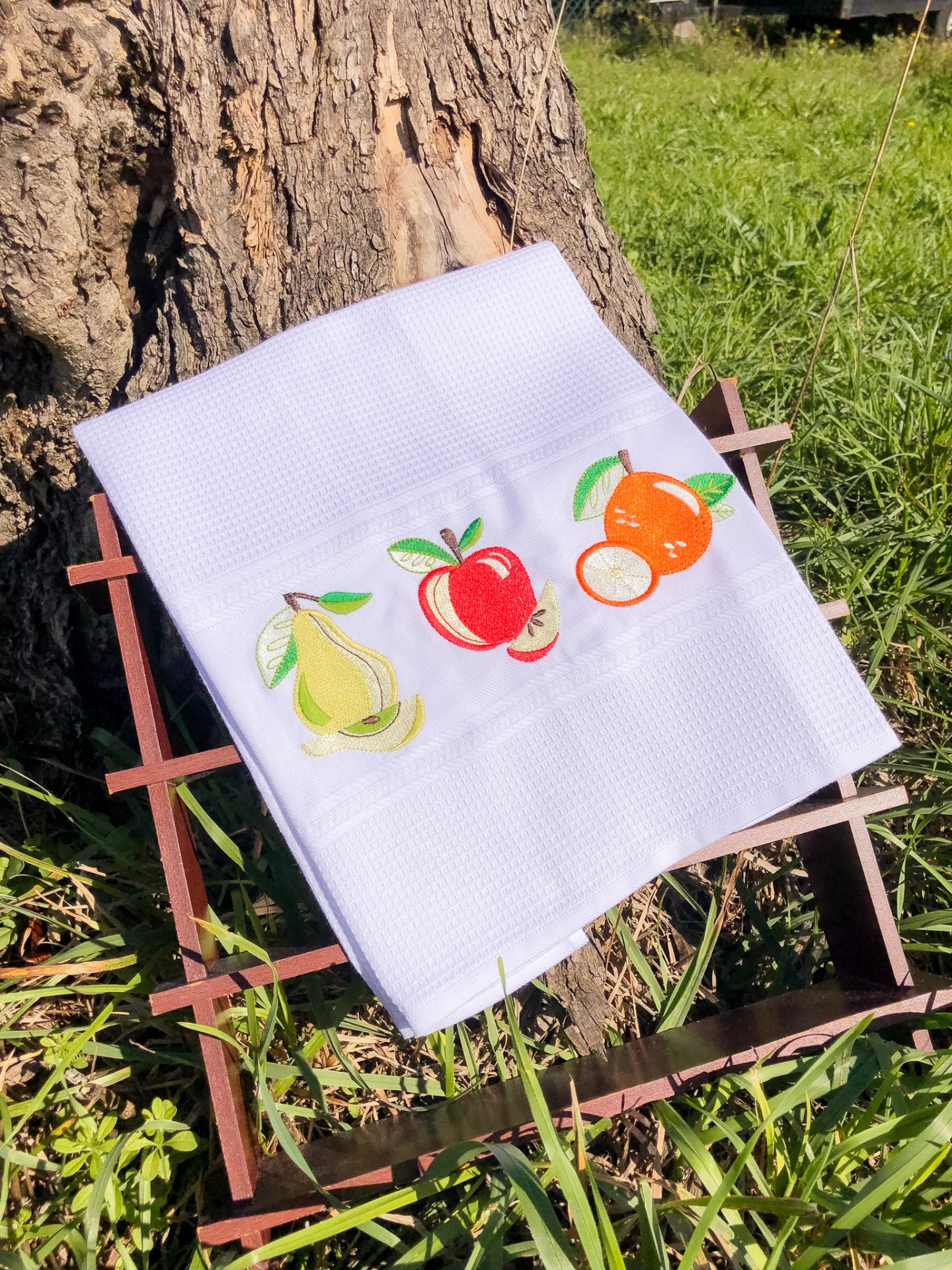 Toalha branca bordada com frutas sobre suporte de madeira ao ar livre