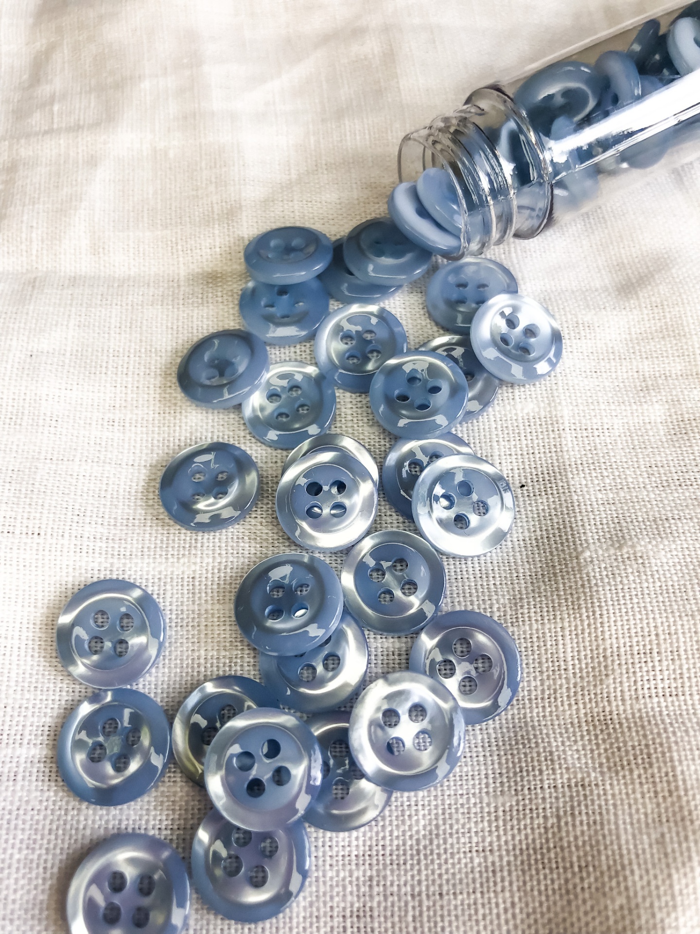 Botões azuis brilhantes espalhados sobre tecido bege
