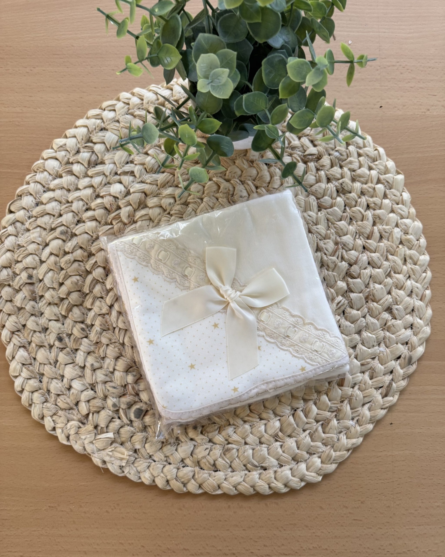 Toalha ou lenço branco com estrelas douradas, renda e laço sobre suporte trançado