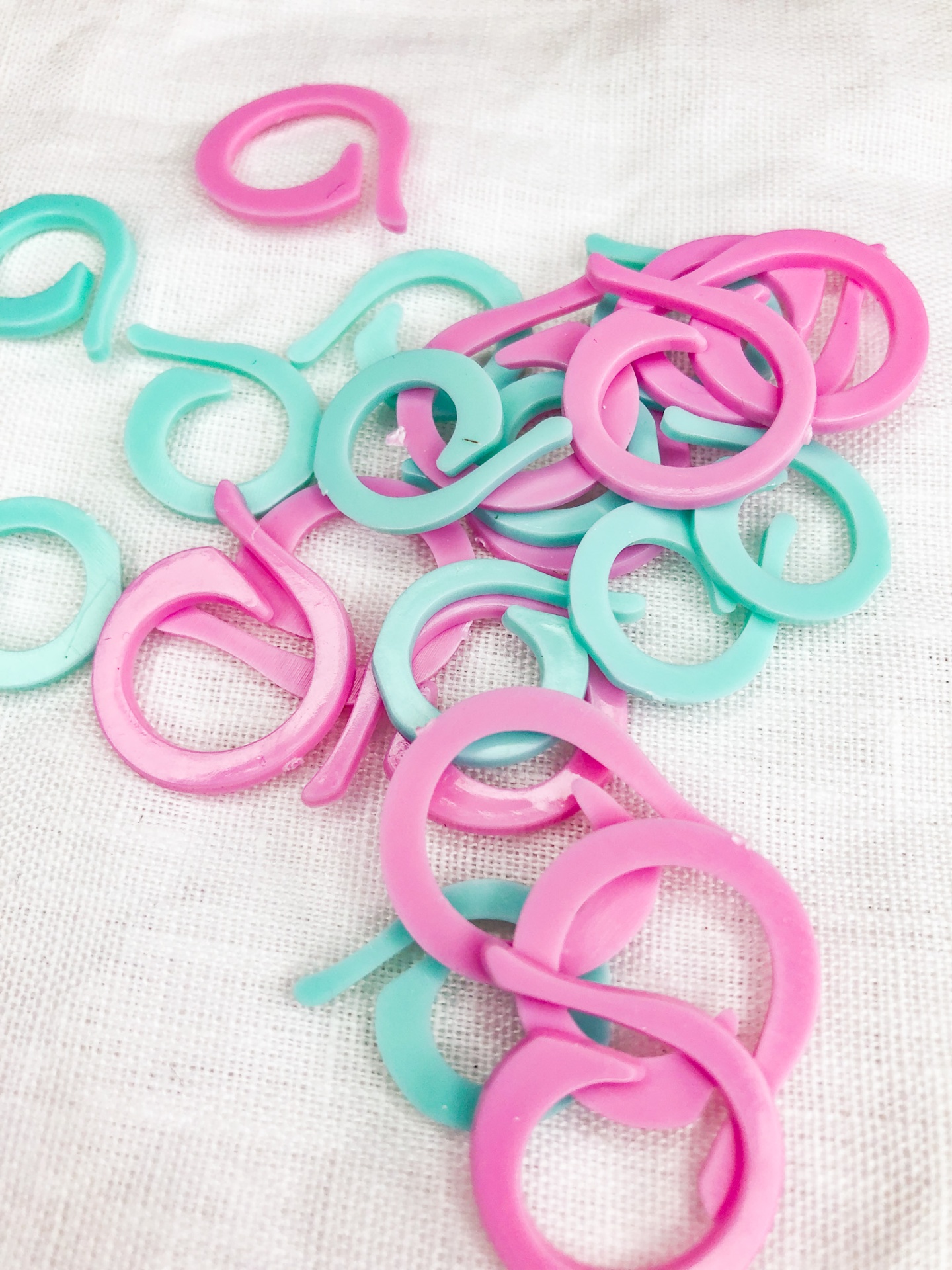 Argolas de plástico rosa e verde água sobre tecido branco