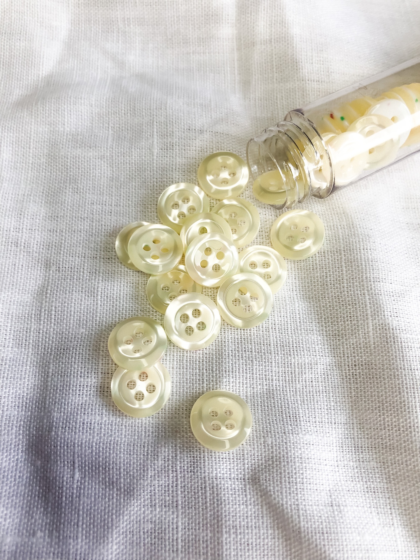 Botões de plástico translúcido cor de pérola sobre tecido branco