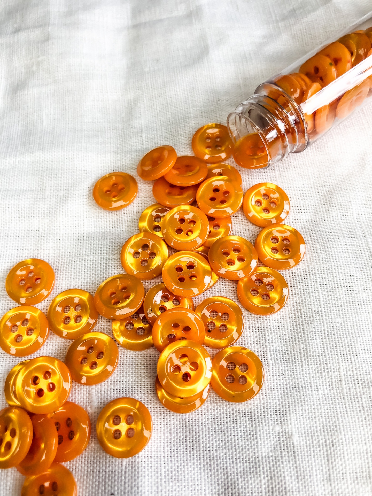 Botões laranja translúcidos de vários tipos espalhados em tecido branco
