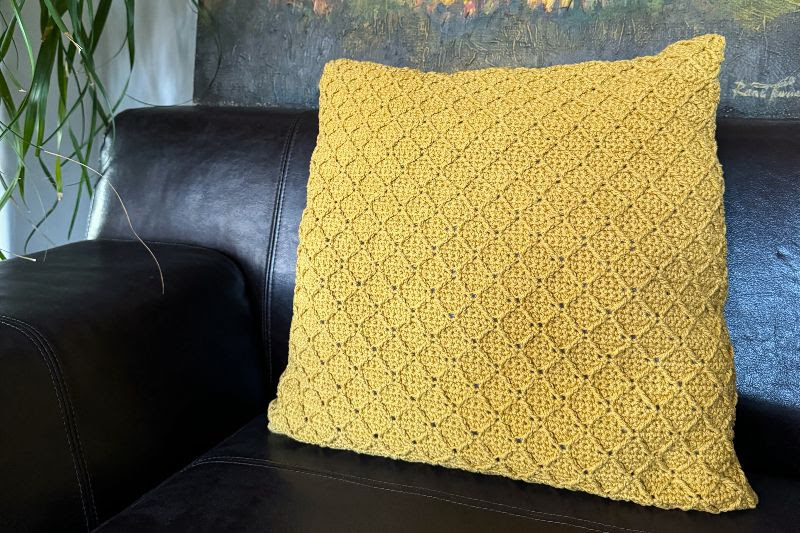 Almofada amarela texturizada num sofá de pele preto