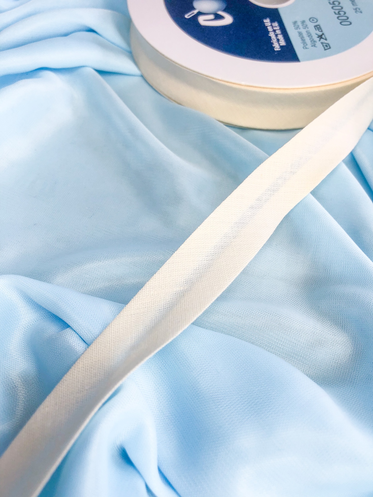 Fita adesiva branca de tecido sobre tecido azul claro com rolo ao lado