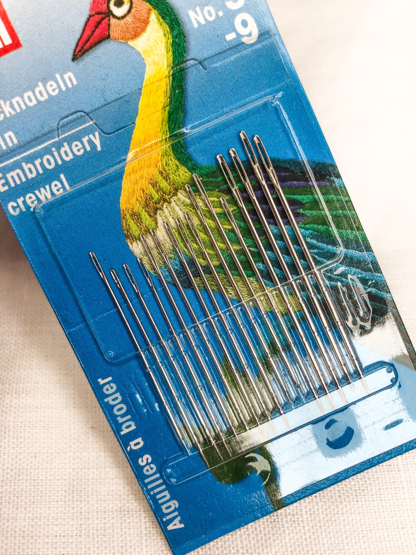 Conjunto de agulhas de bordar em embalagem azul com pássaro colorido