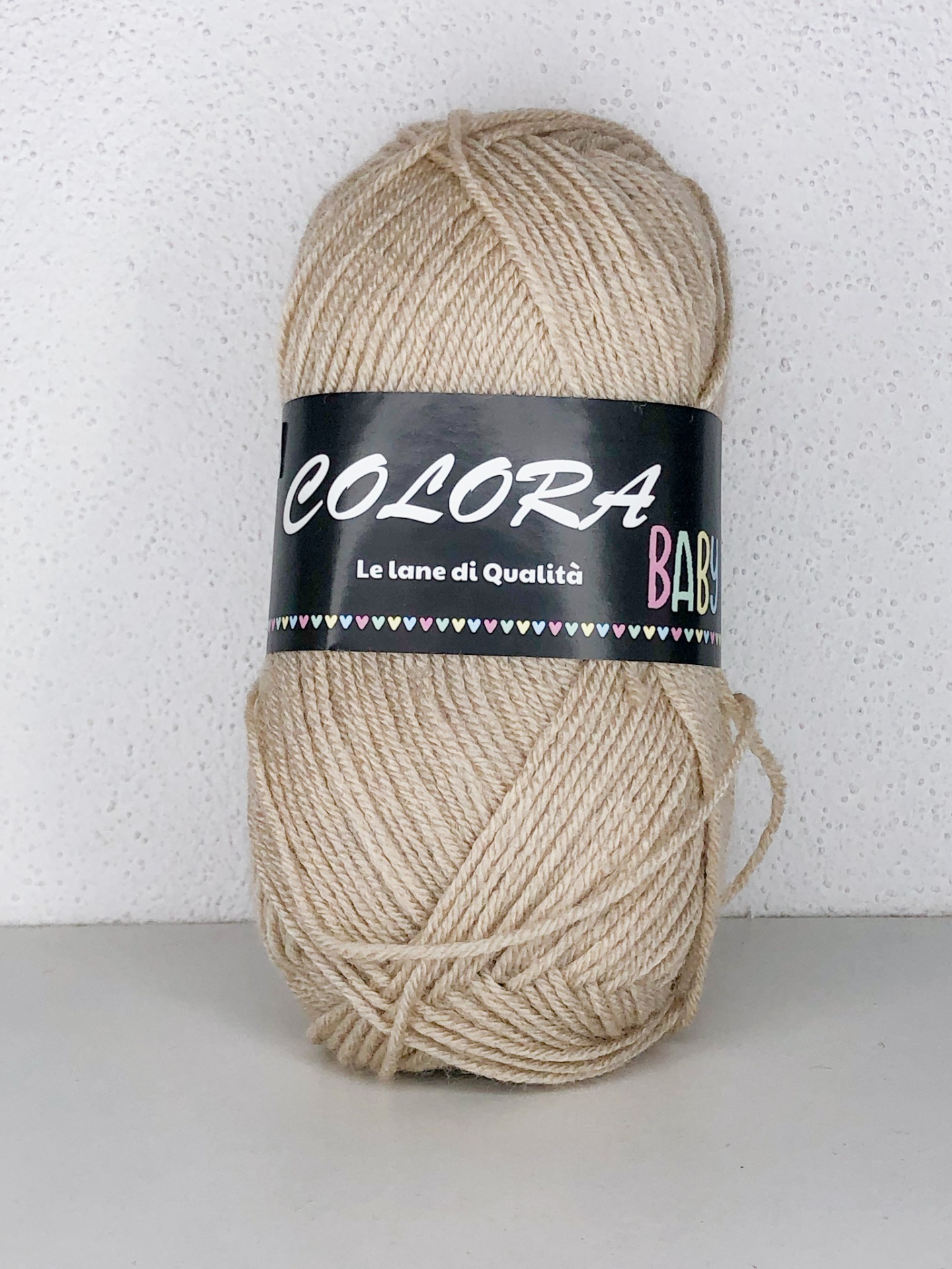 Novelo de lã bege claro com etiqueta preta em fundo branco