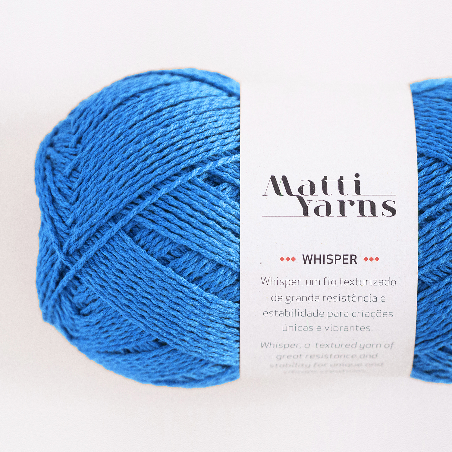 Novelo de lã azul com etiqueta branca Matti Yarns Whisper sobre fundo branco