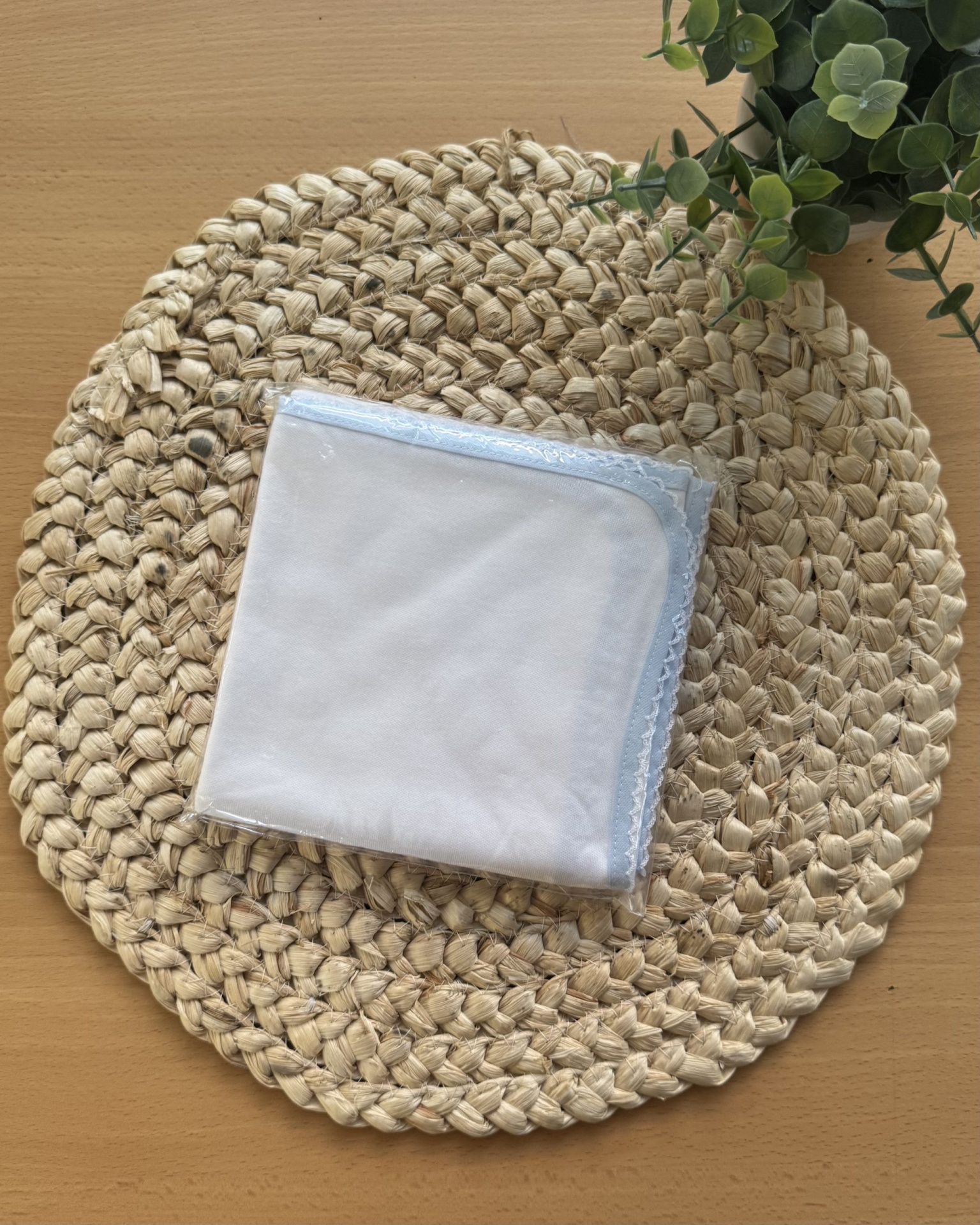 Guardanapo branco com bordo azul sobre jogo americano de palha trançada