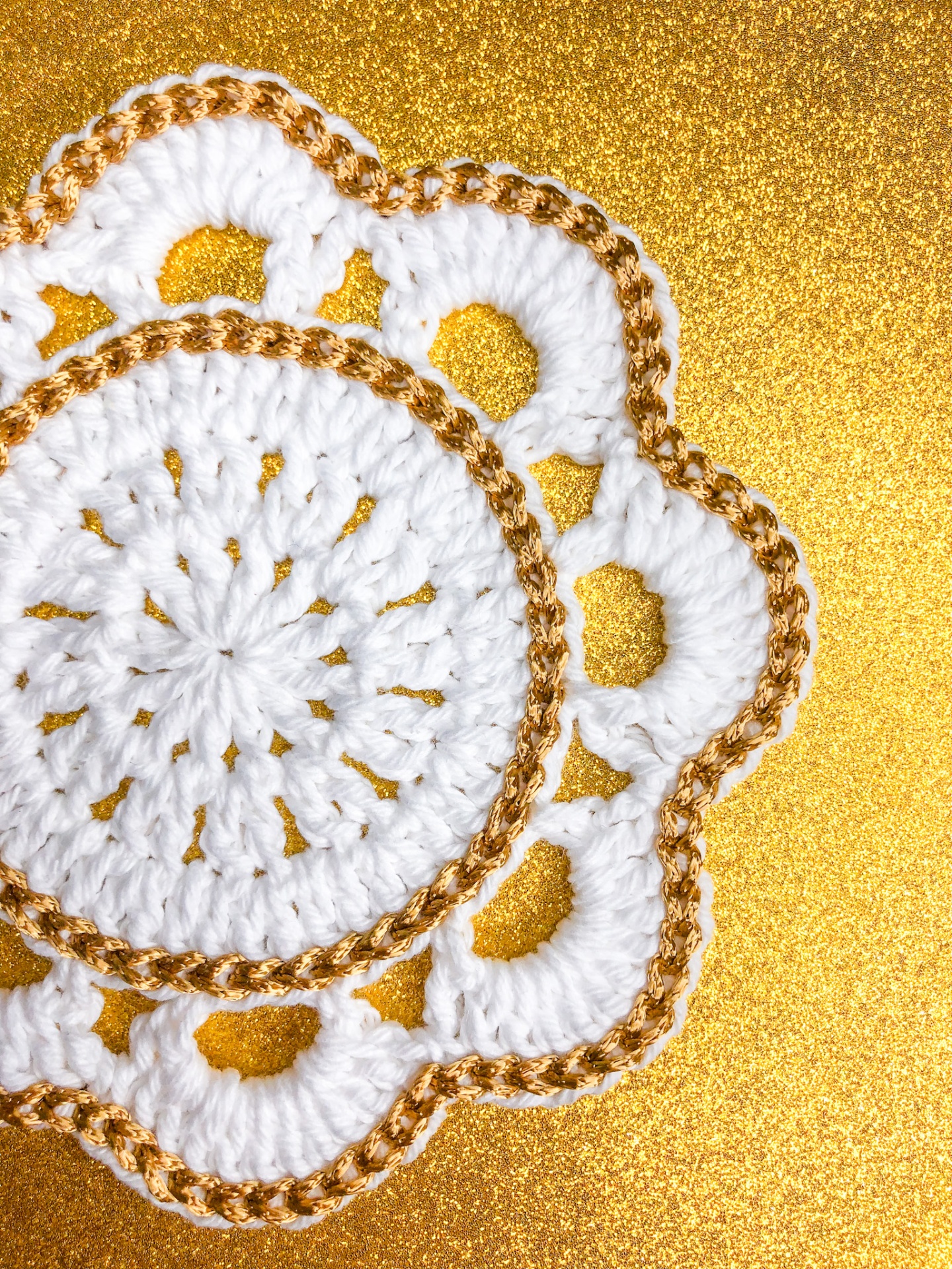 Centro de mesa em crochet branco e dourado sobre fundo dourado