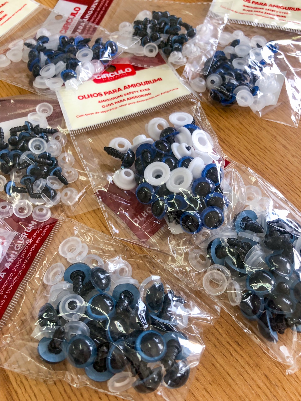 Pacotes de olhos de segurança para amigurumi em várias cores sobre madeira