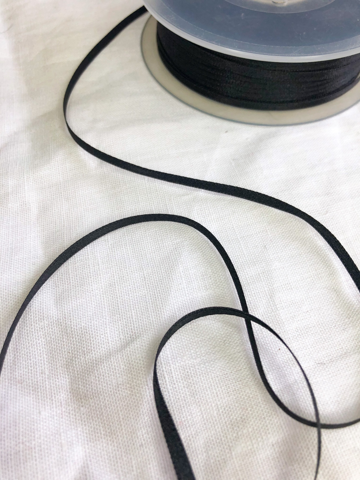 Rolo de fita preta fina sobre superfície branca